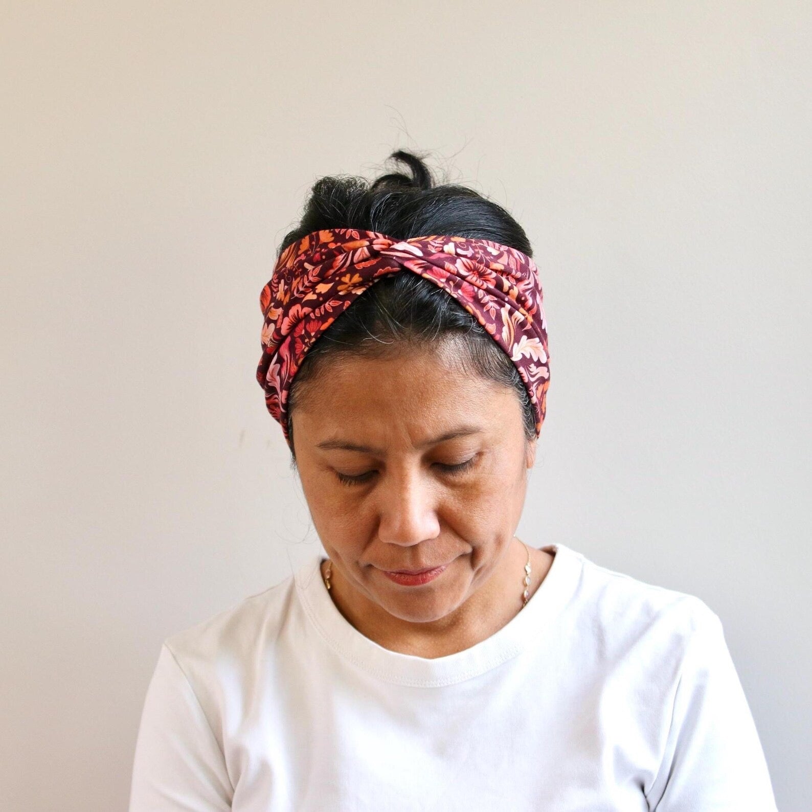 Woman wearing a patterned headband against a plain background