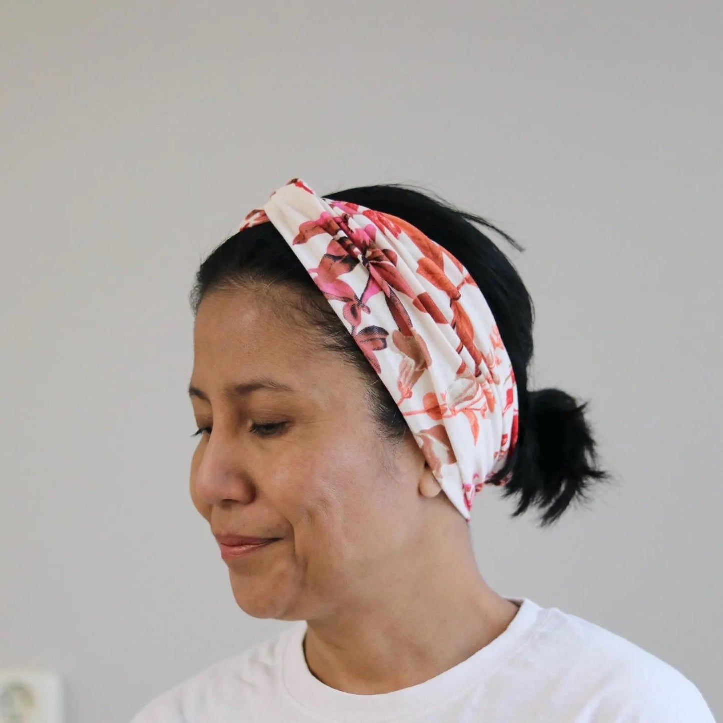 Woman wearing a floral headband against a plain background