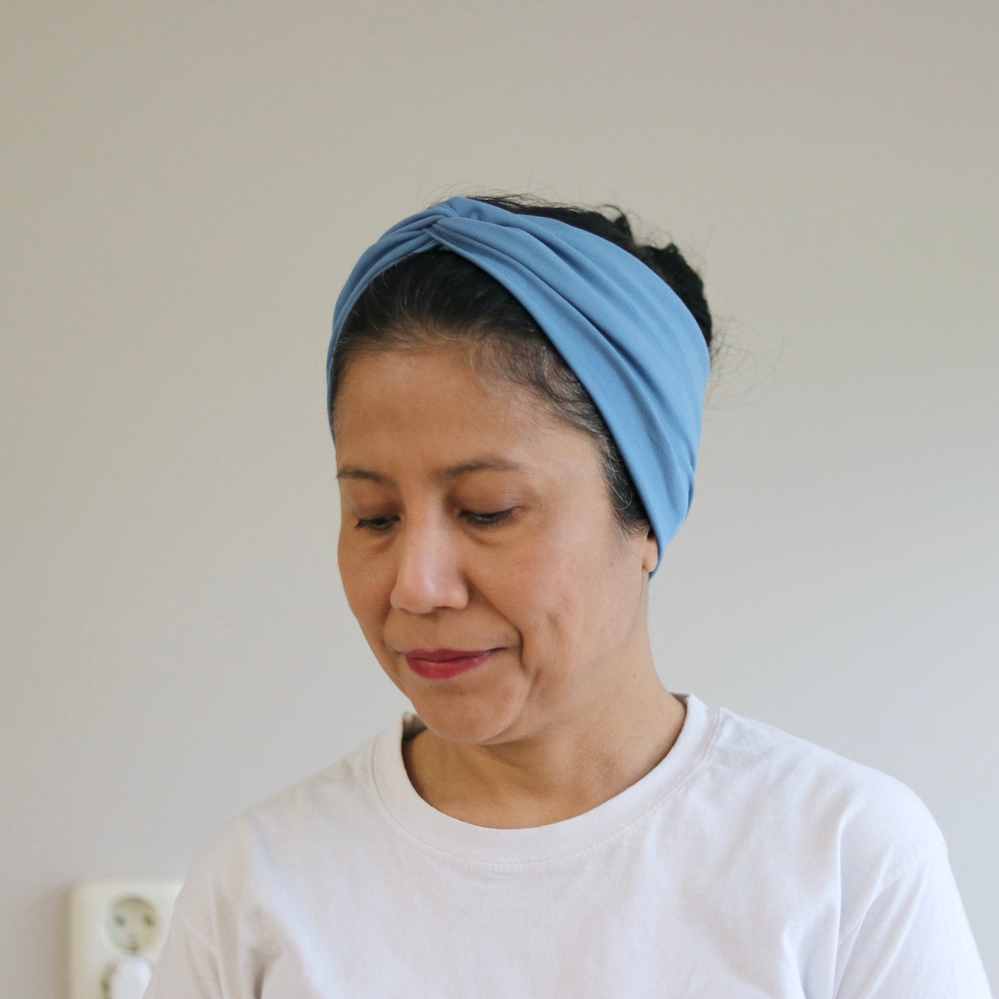 Woman wearing a blue headband against a plain background