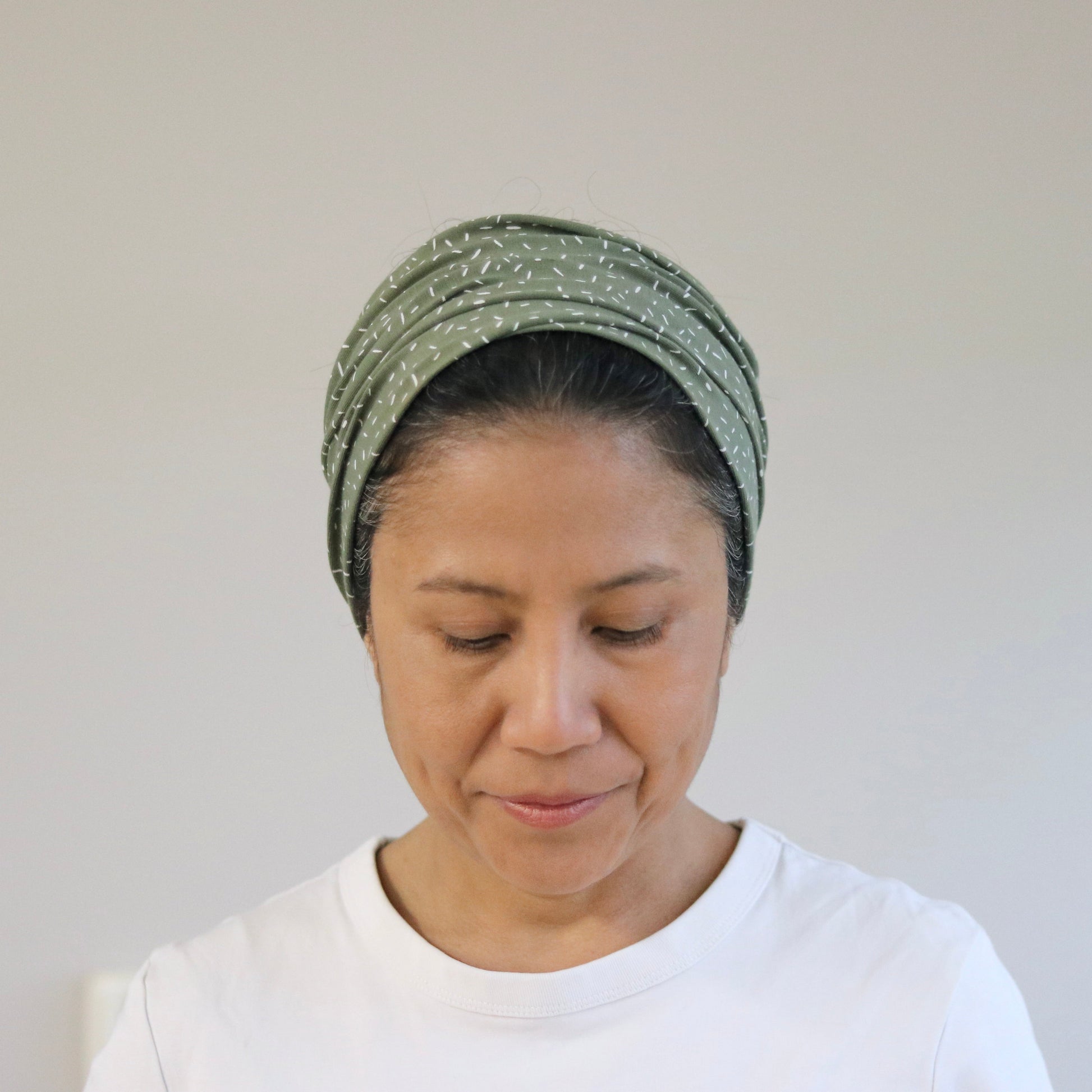 Woman wearing a green headscarf against a plain background