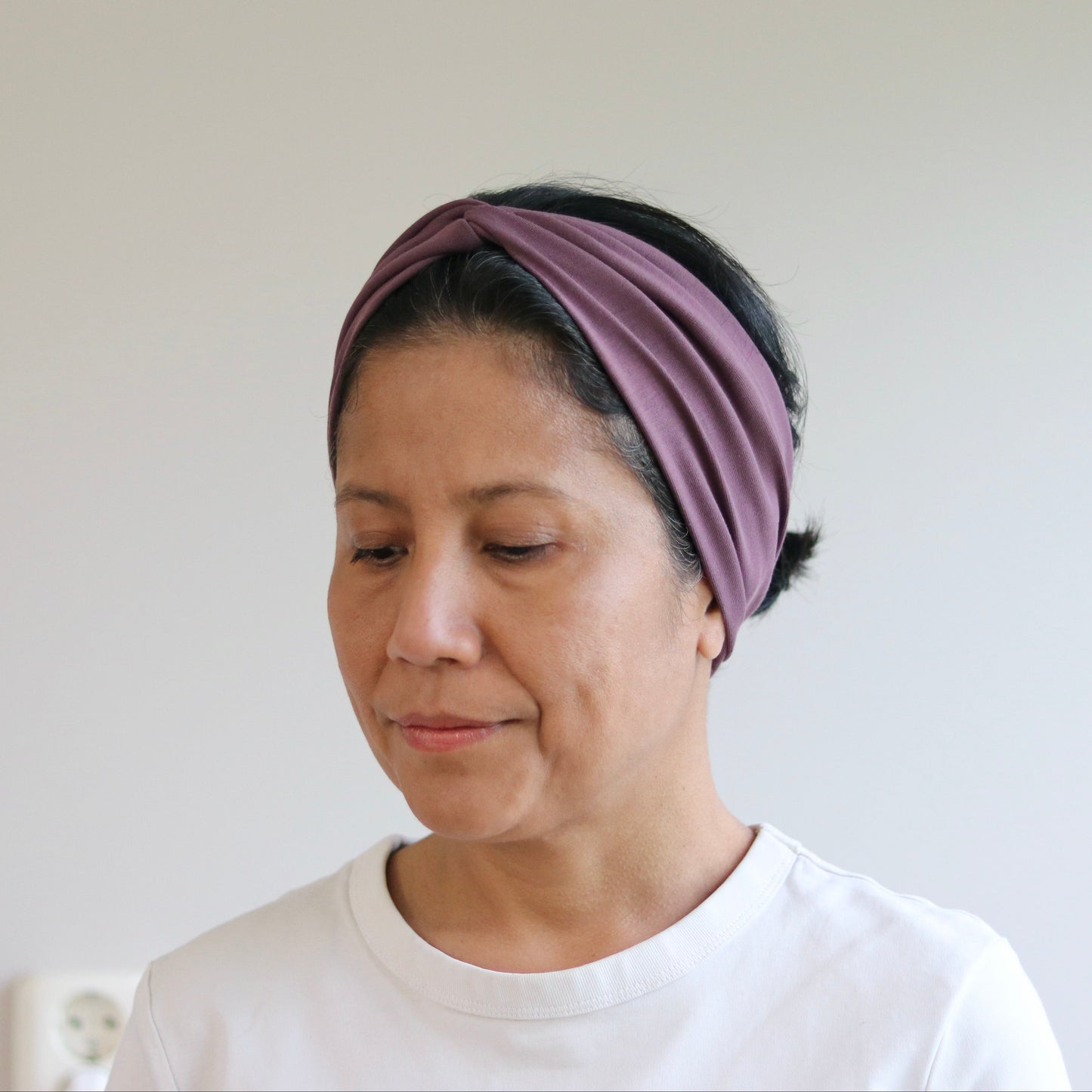 Woman wearing a purple headband against a plain background