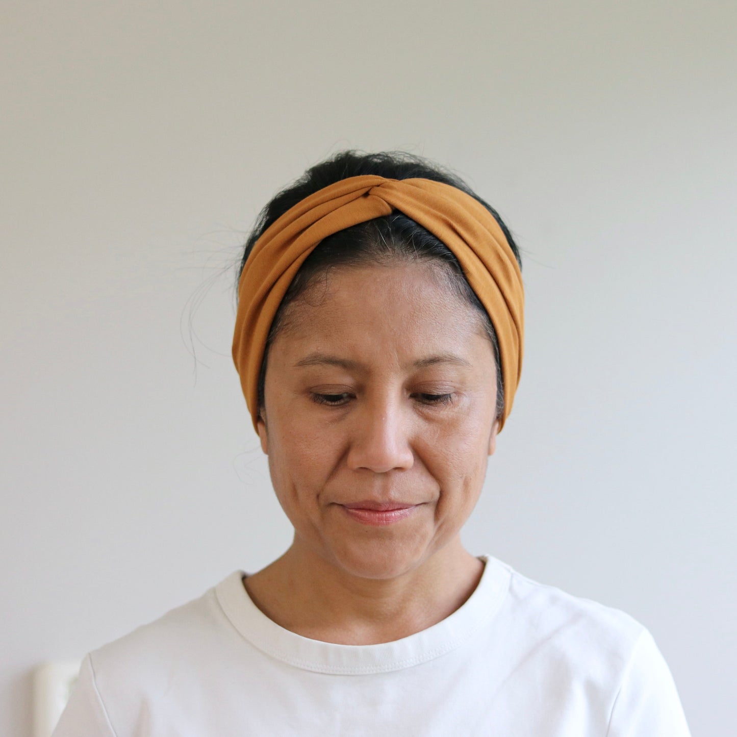 Woman wearing a yellow headband against a plain background