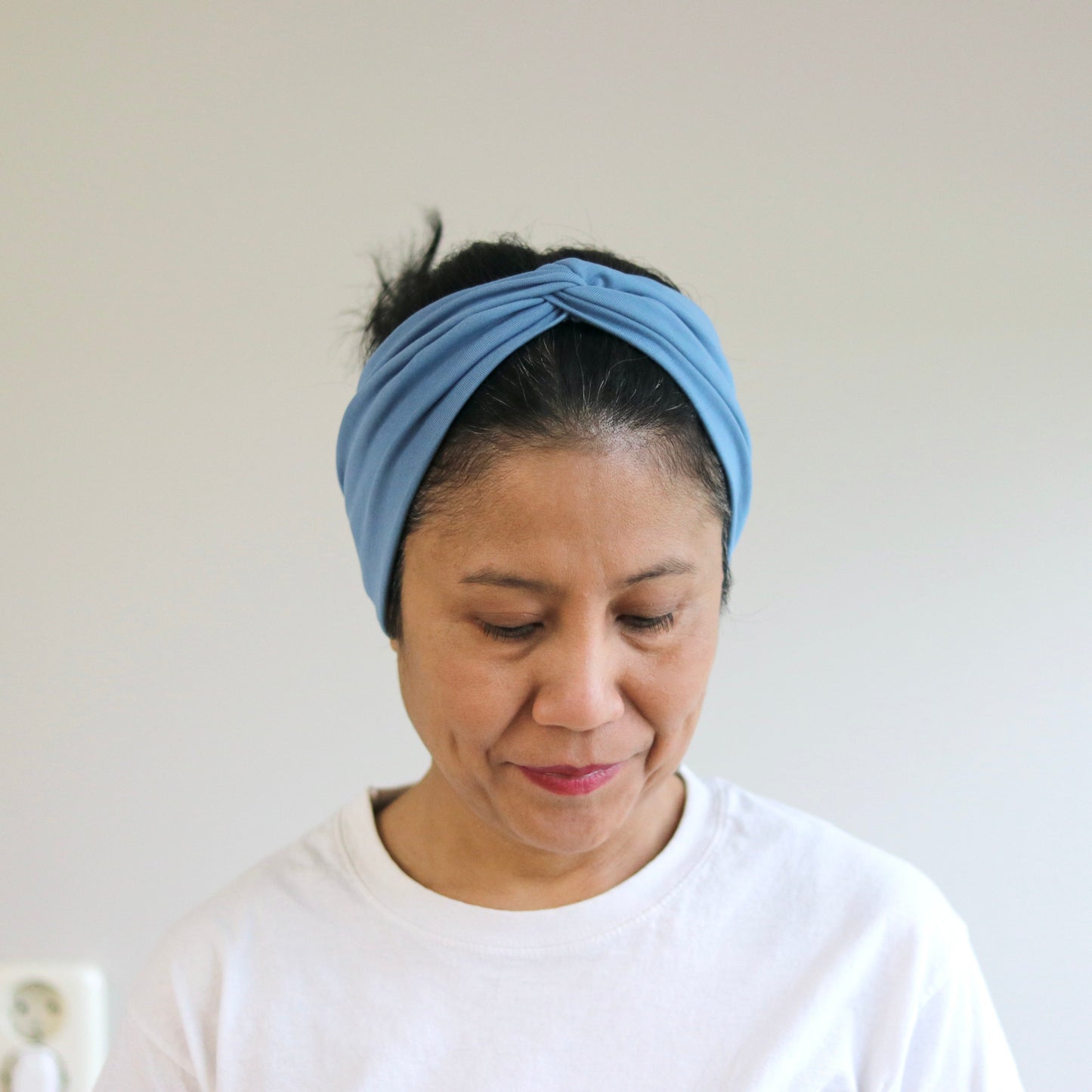 Woman wearing a blue headband against a plain background