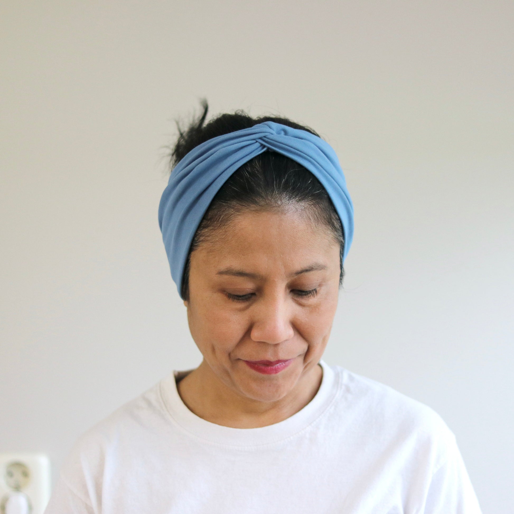 Woman wearing a blue headband against a plain background