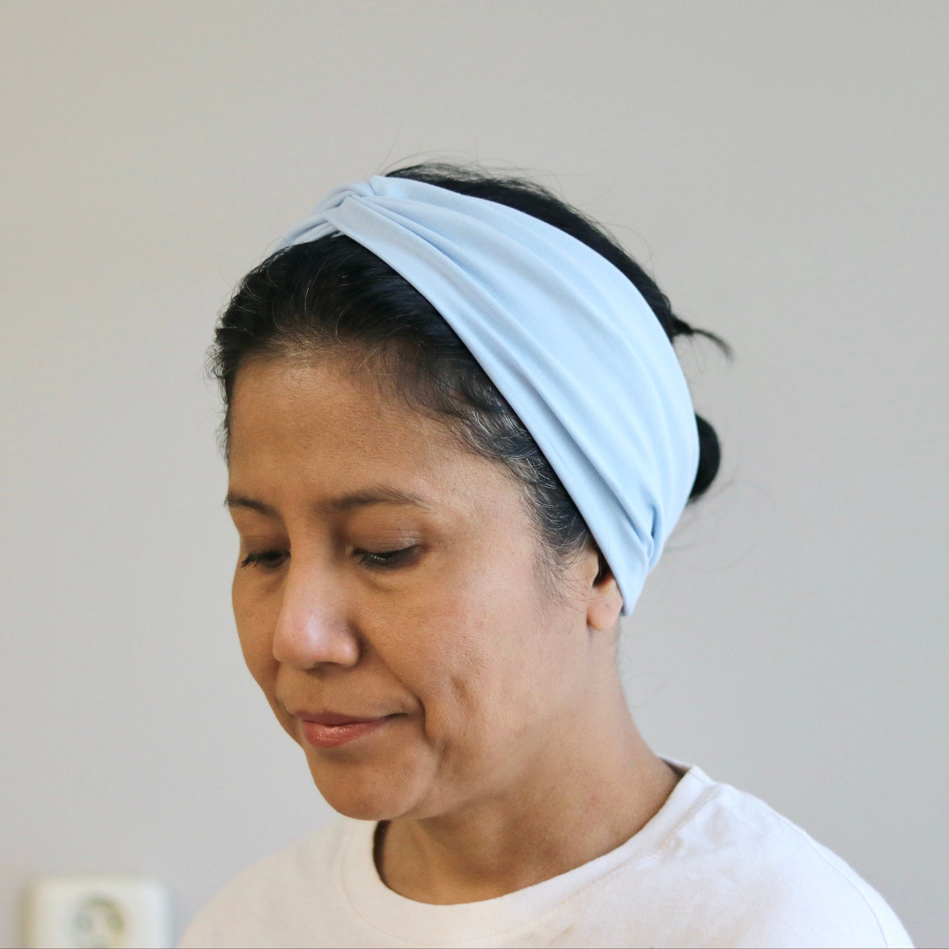 Woman wearing a light blue headband against a plain background