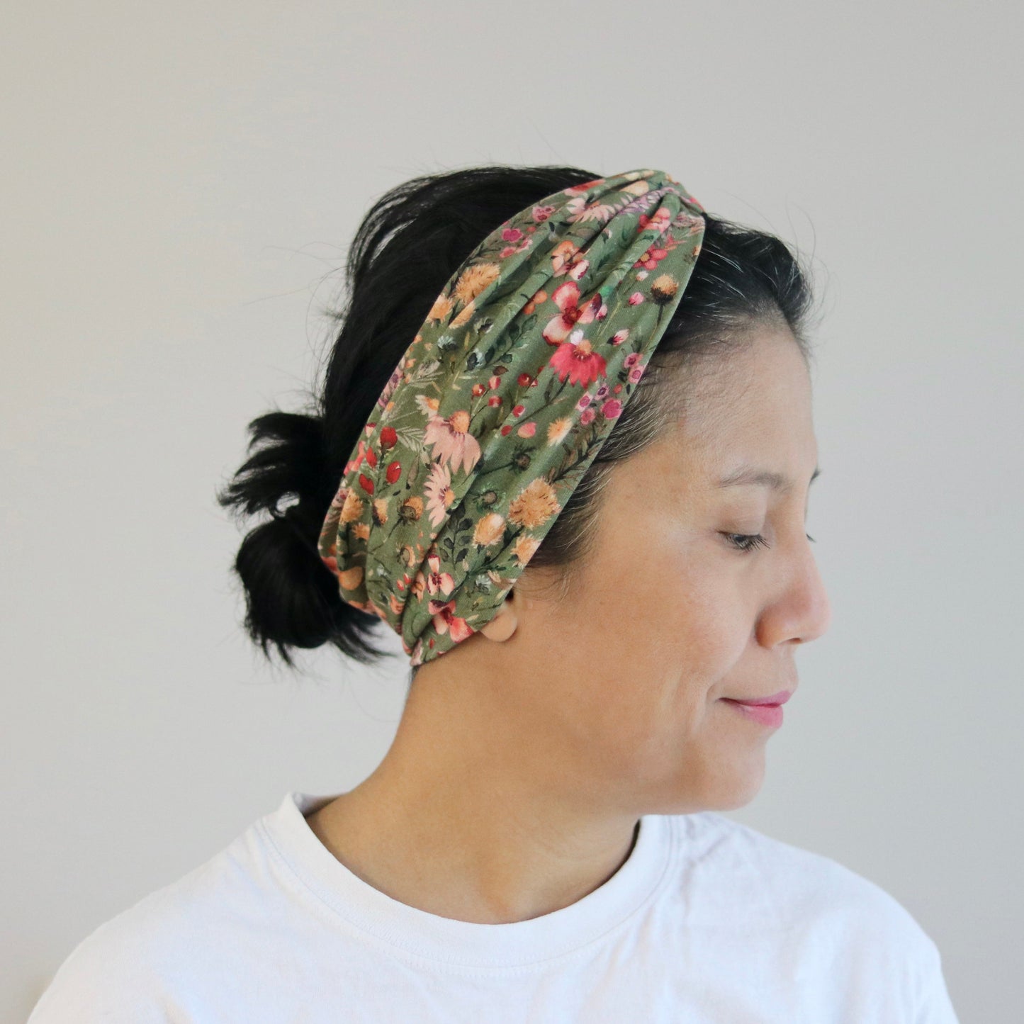 Woman wearing a floral headband against a plain background