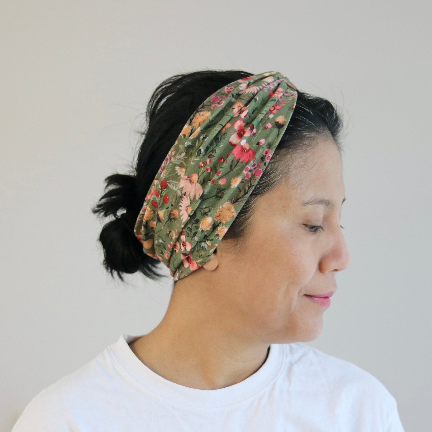 Woman wearing a floral headband against a plain background