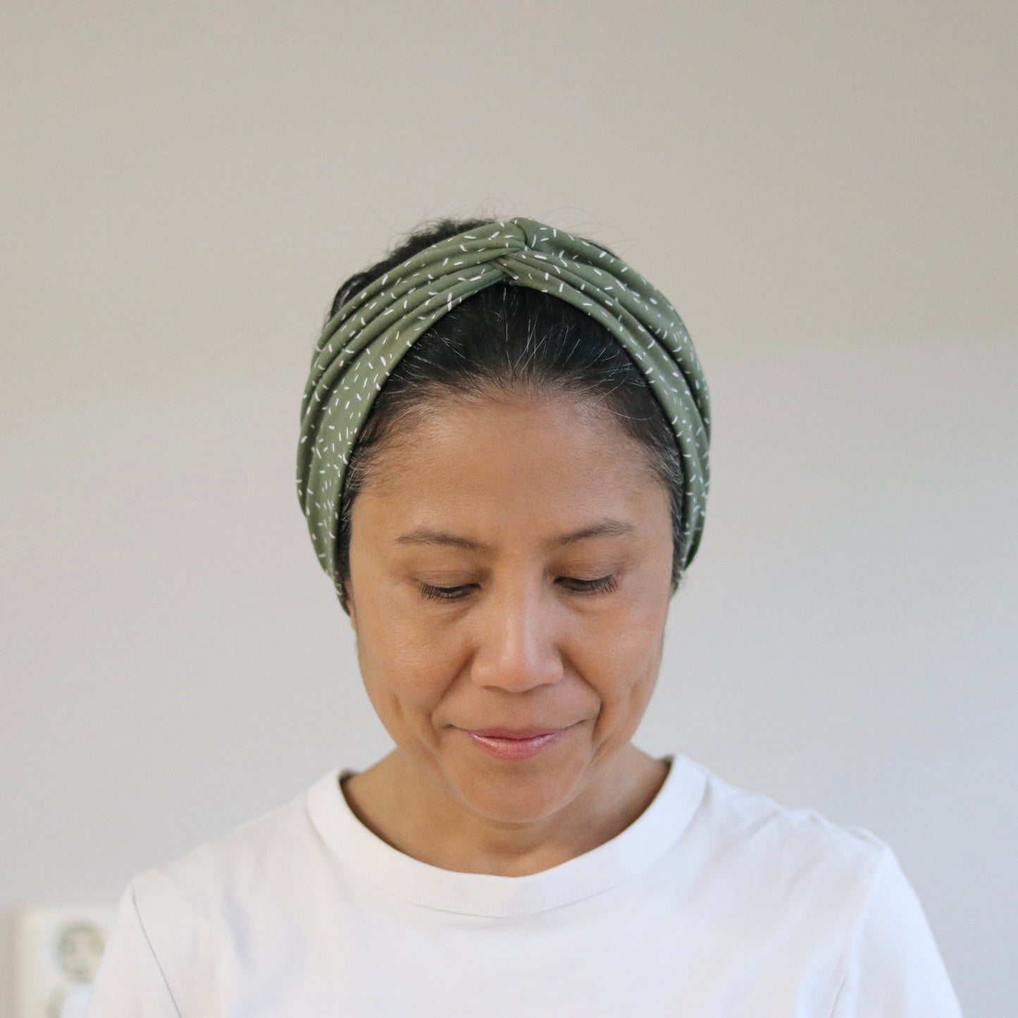 Woman wearing a green headband against a plain background