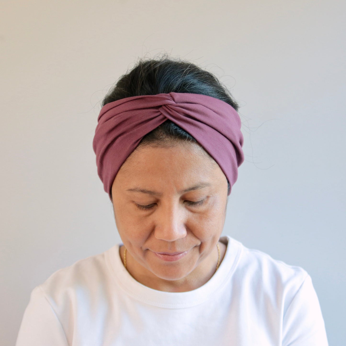 Woman wearing a purple headband against a plain background