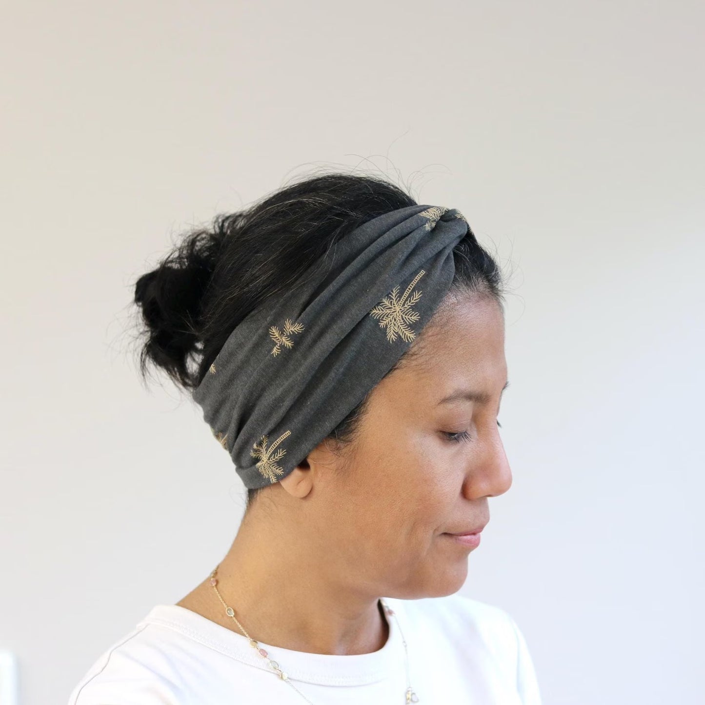 Woman wearing a gray headband with gold patterns against a white background