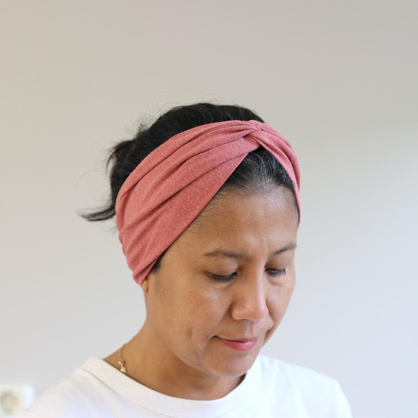 Woman wearing a red- melange headband against a plain background
