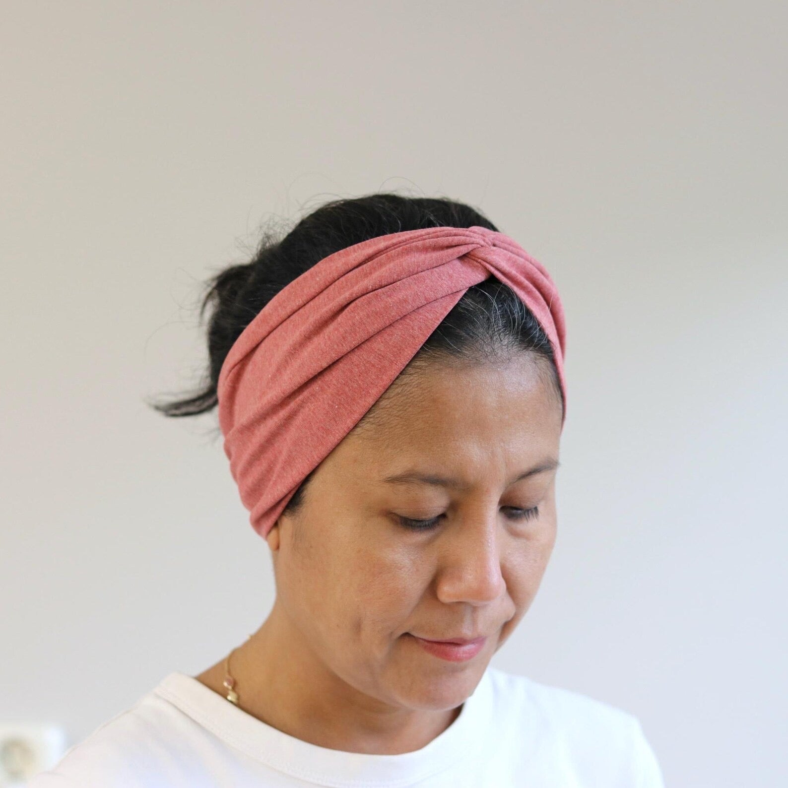 Woman wearing a red- melange headband against a plain background