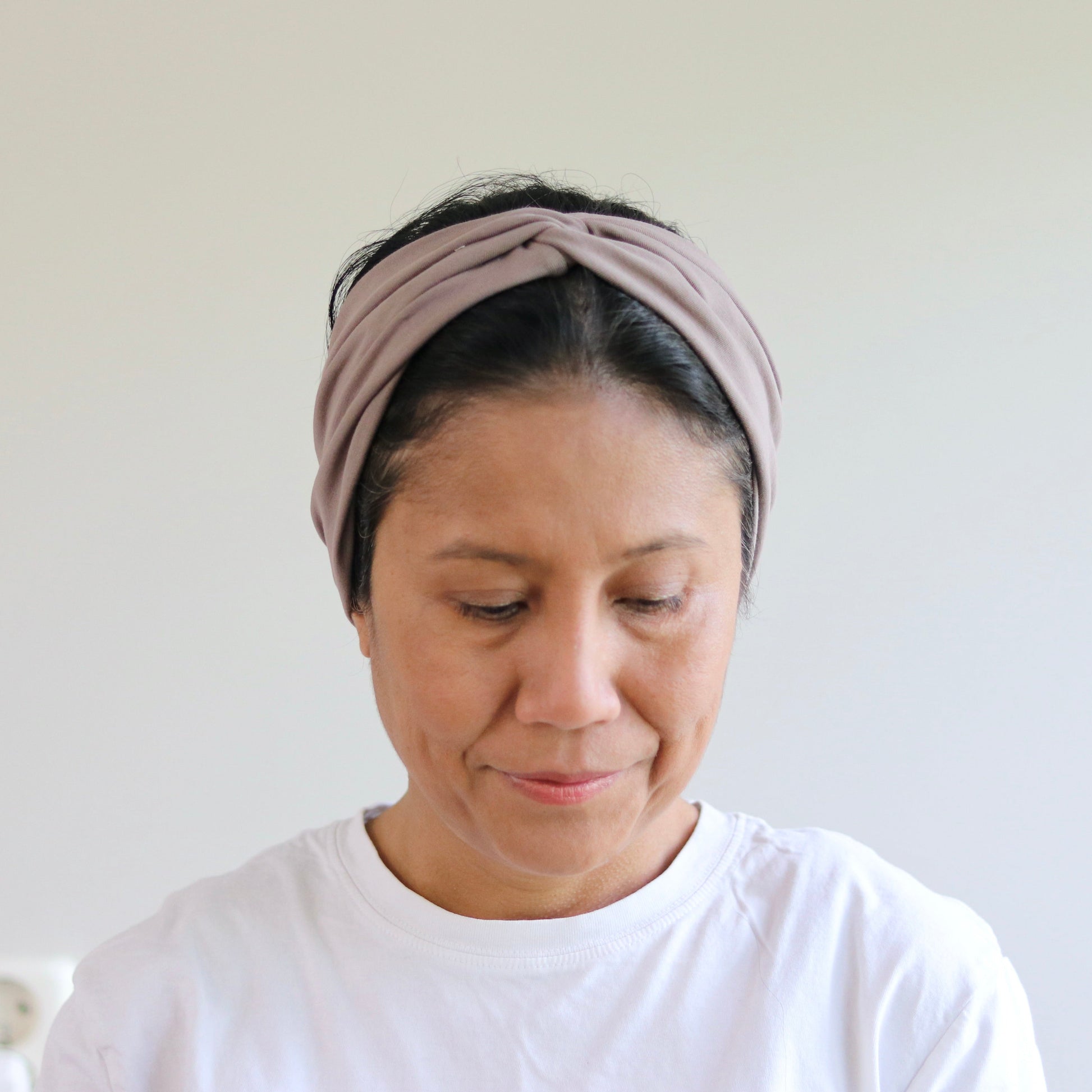 Woman wearing a headband against a plain background