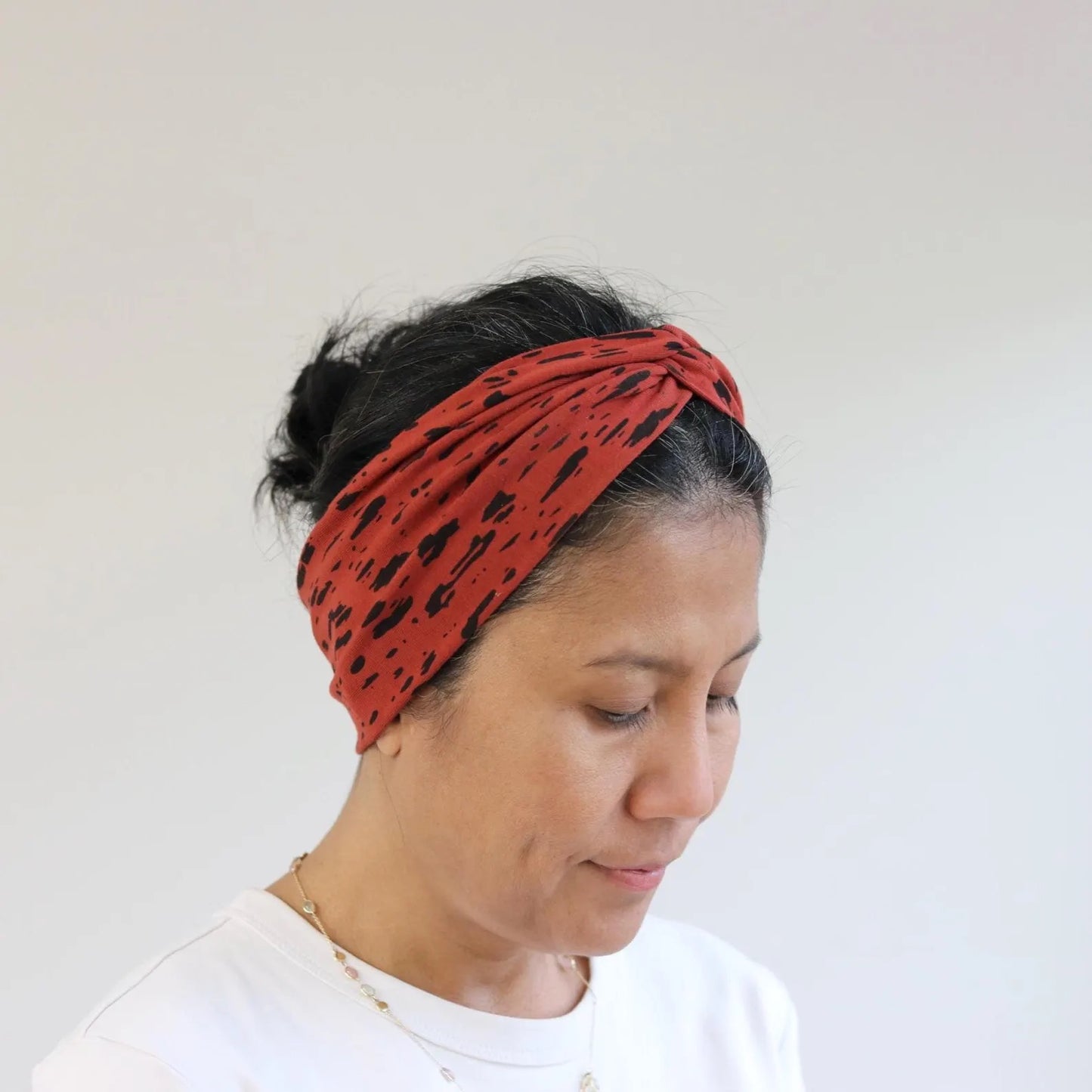 Person wearing a red patterned headband against a plain background