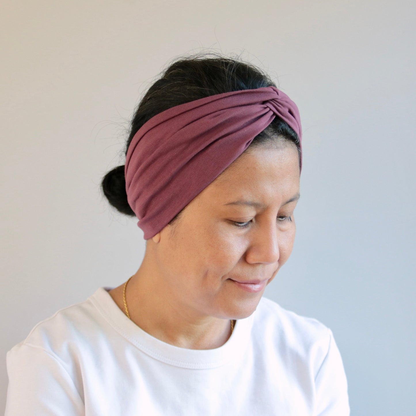 Woman wearing a mauve headband against a plain background