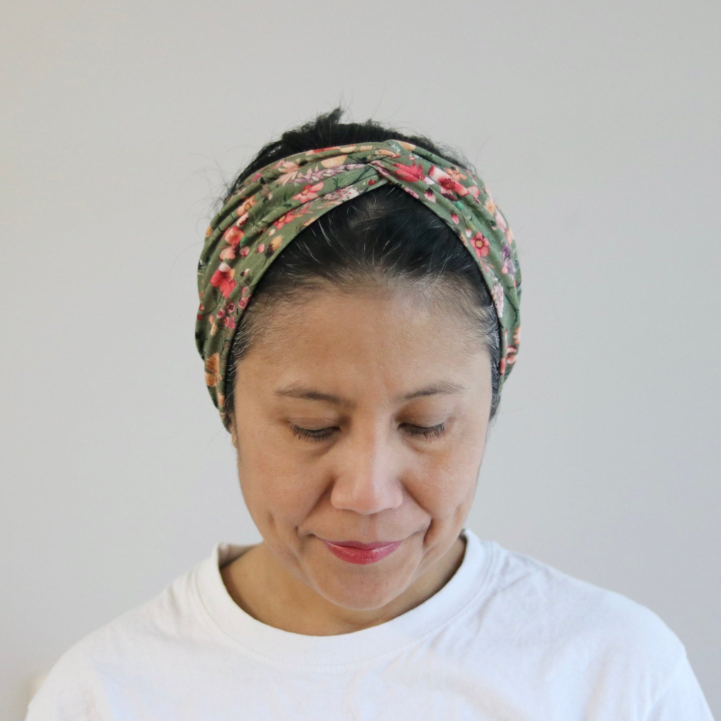 Woman wearing a floral headband against a plain background