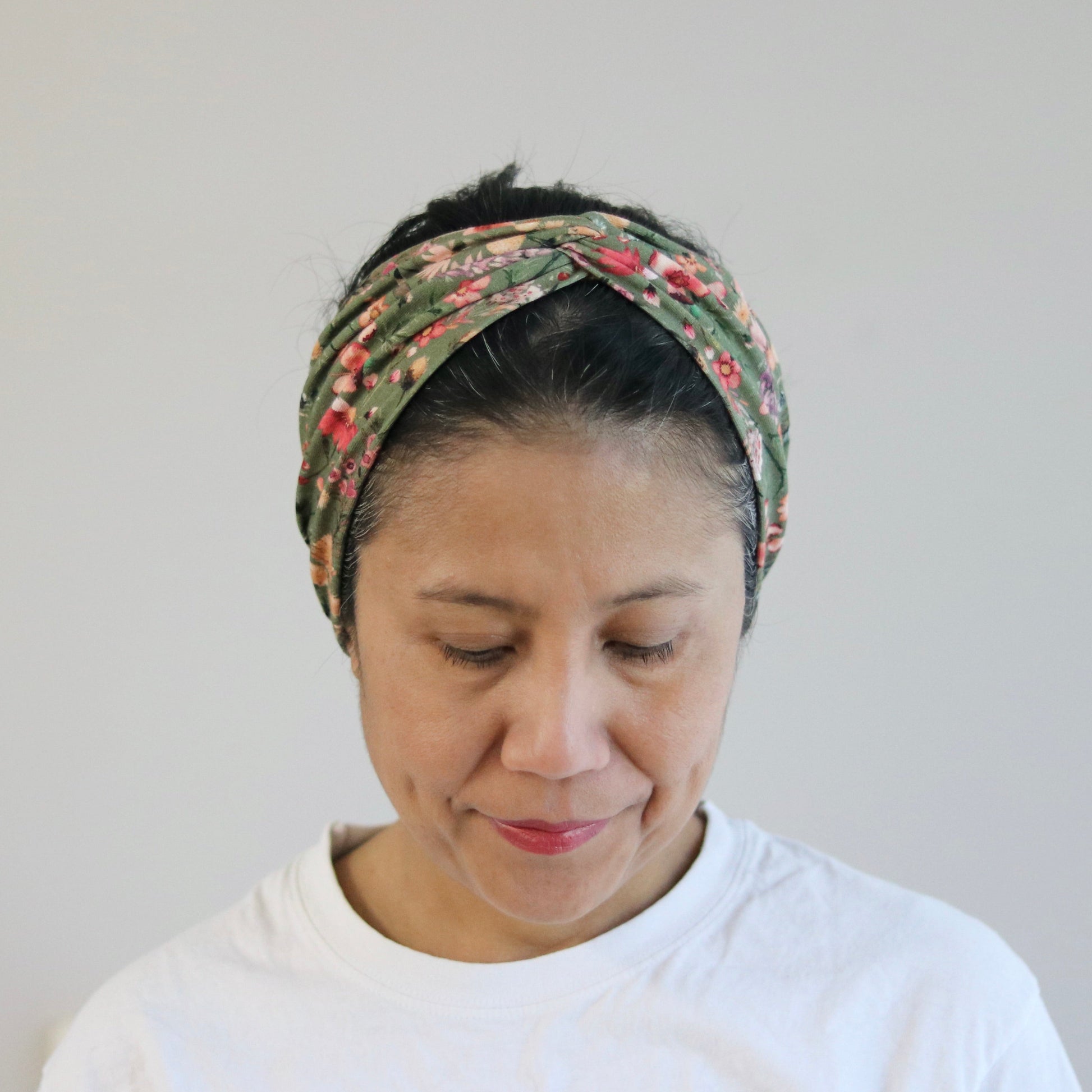 Woman wearing a floral headband against a plain background