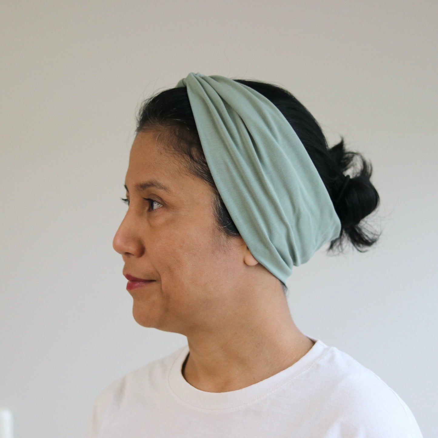 Woman wearing a light green headscarf against a plain background