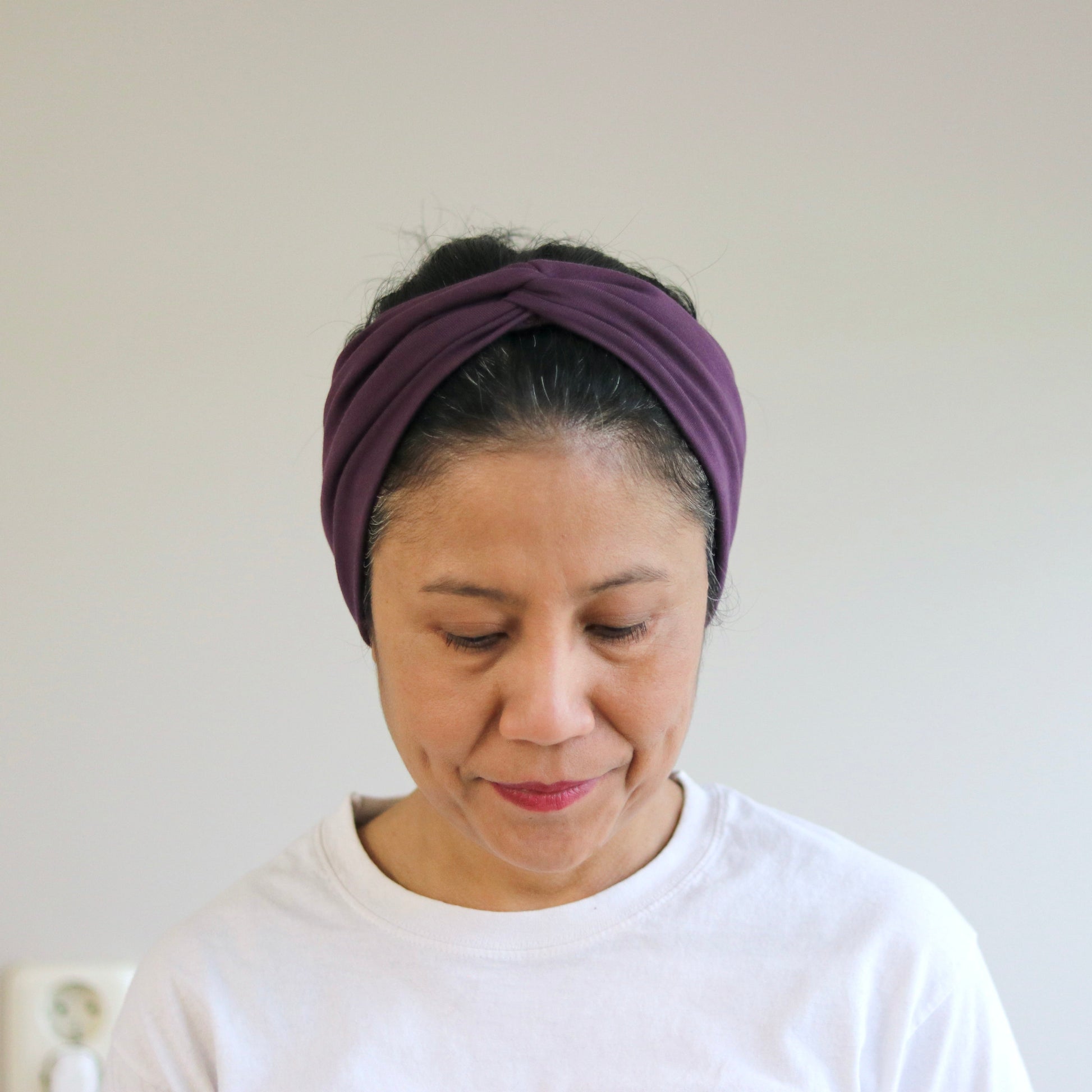 Woman wearing a purple headband against a plain background