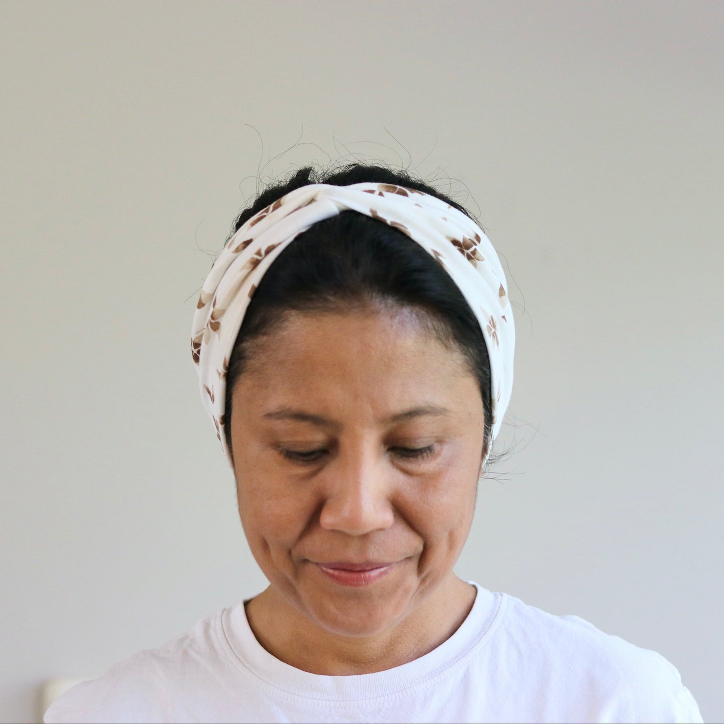 Woman wearing a white headband with a pattern on a plain background