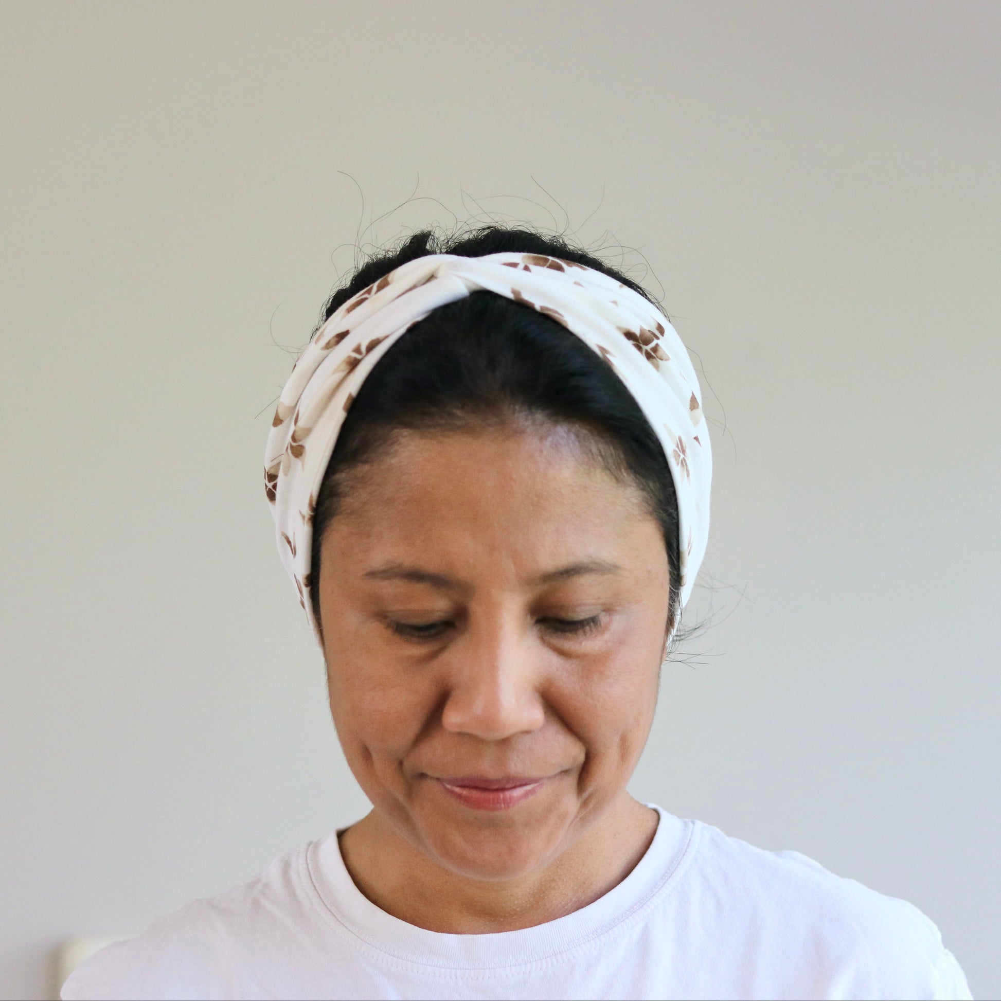 Woman wearing a white headband with a pattern on a plain background