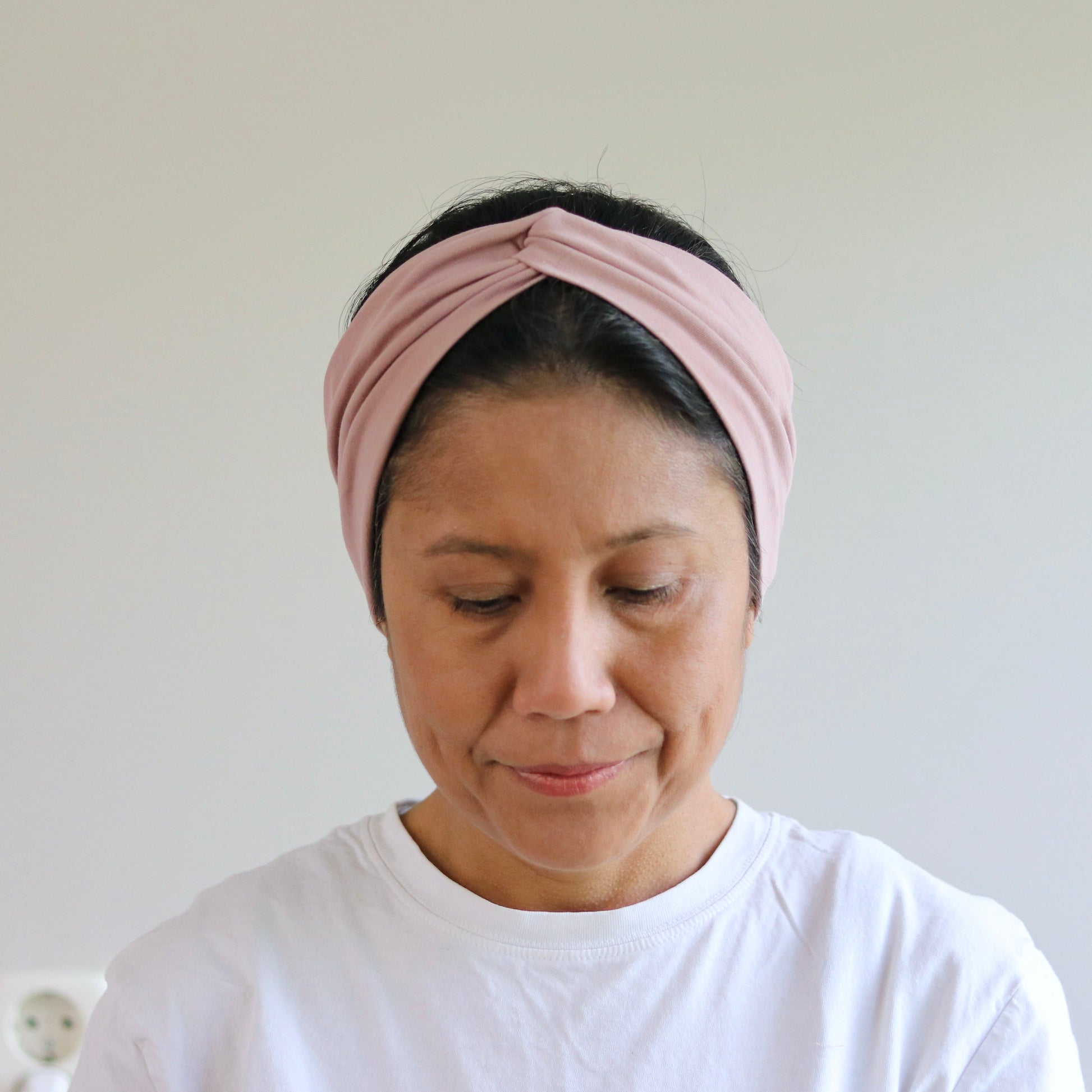 Woman wearing a pink headband against a plain background