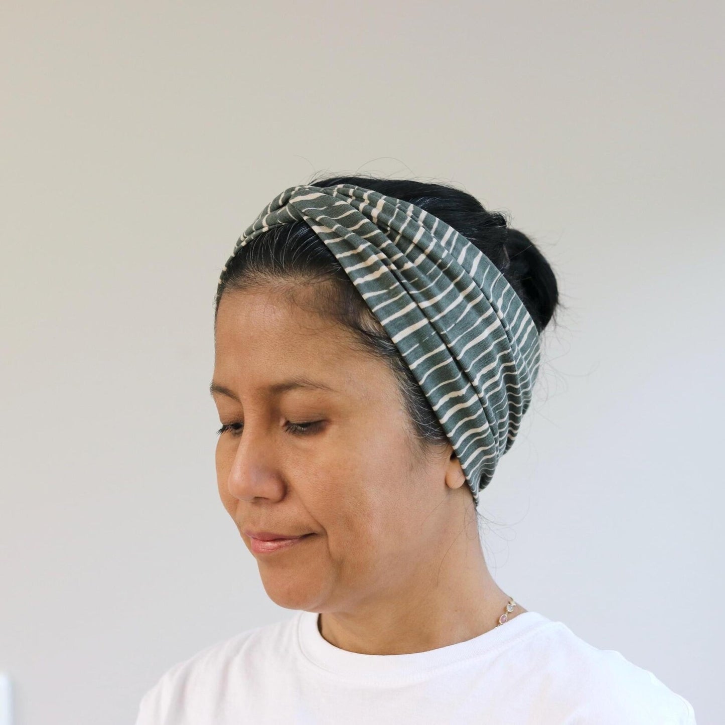 Woman wearing a patterned headscarf on a plain background