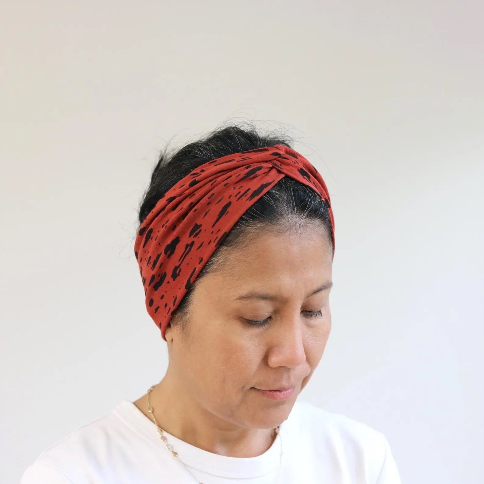 Person wearing a red headband with black patterns on a plain background