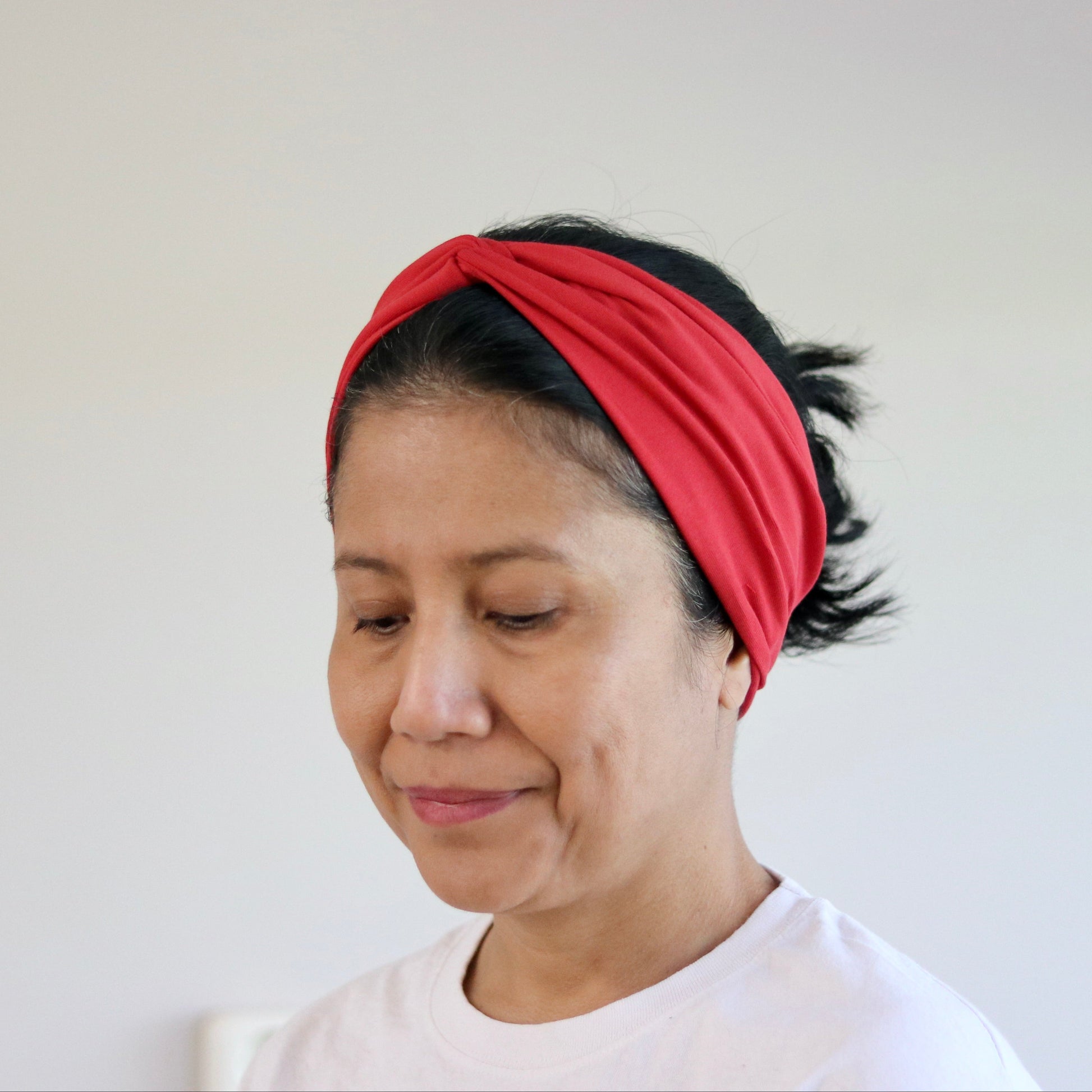 Woman wearing a red headband against a plain background