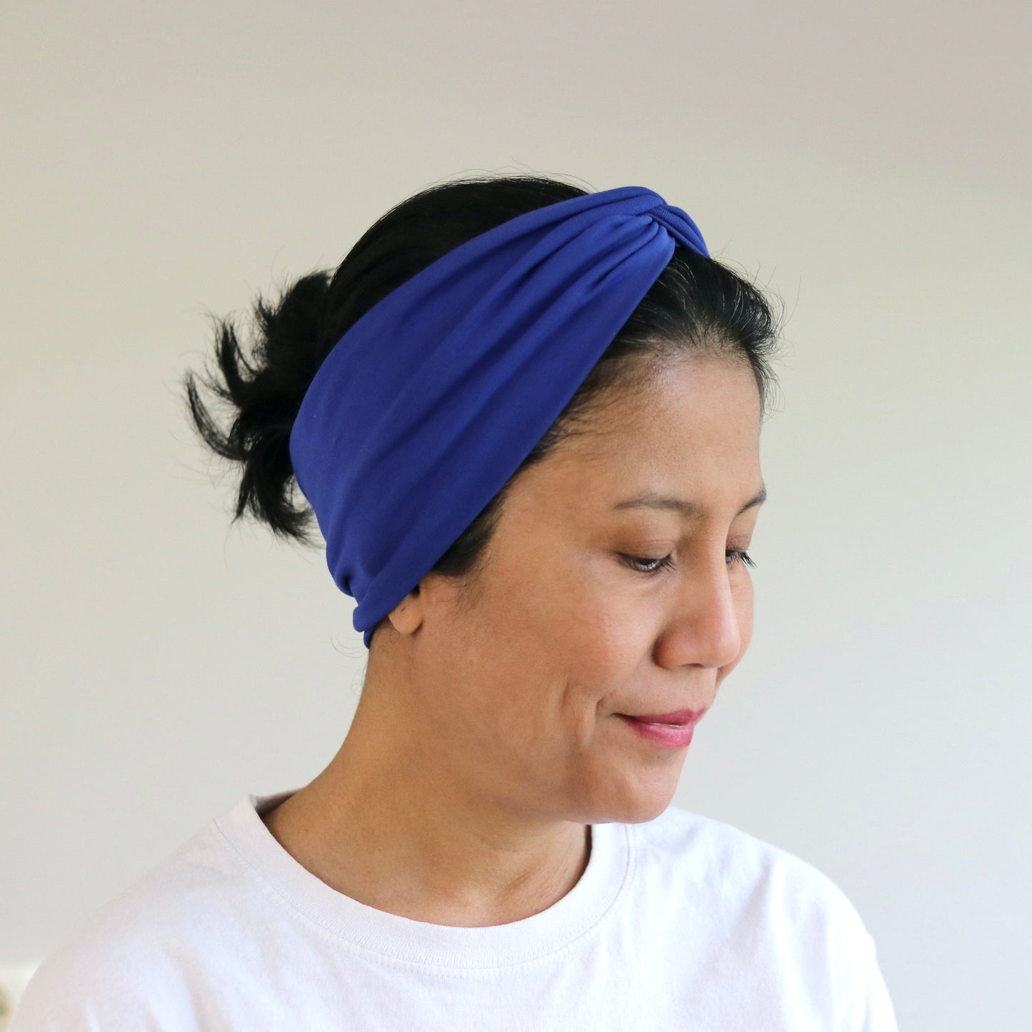 Woman wearing a blue headband against a plain background
