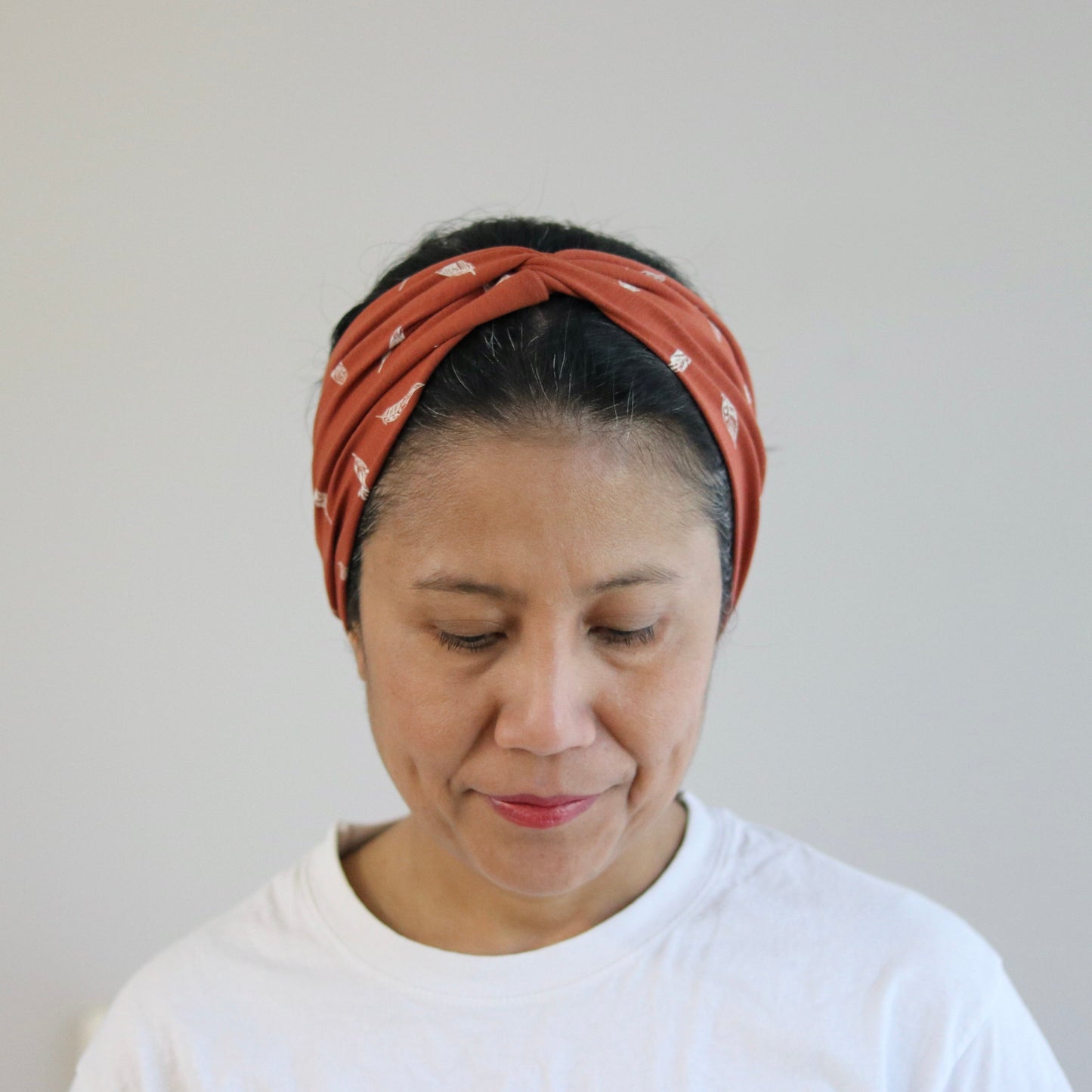 Woman wearing a rust headband against a plain background