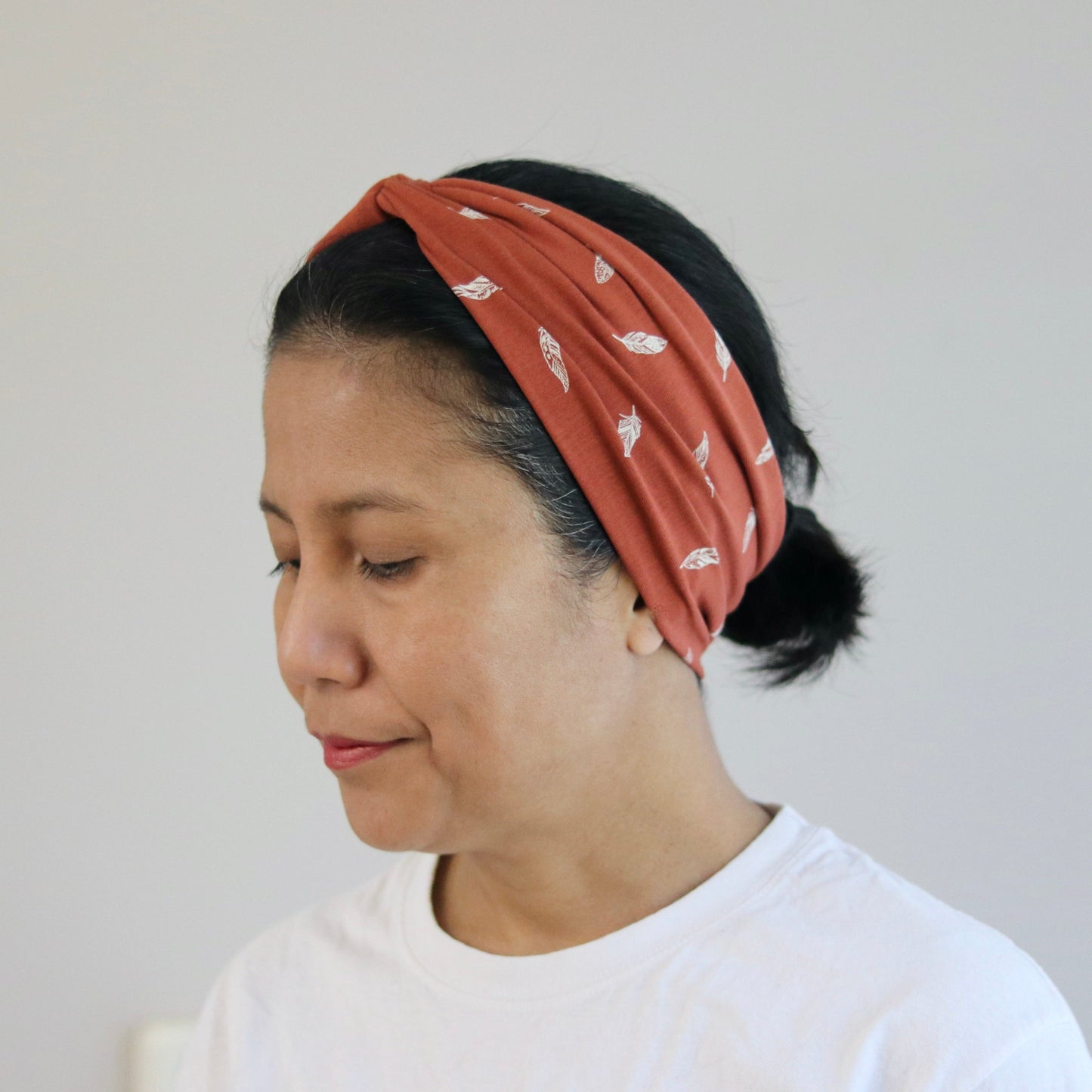 Woman wearing a rust patterned headband against a plain background