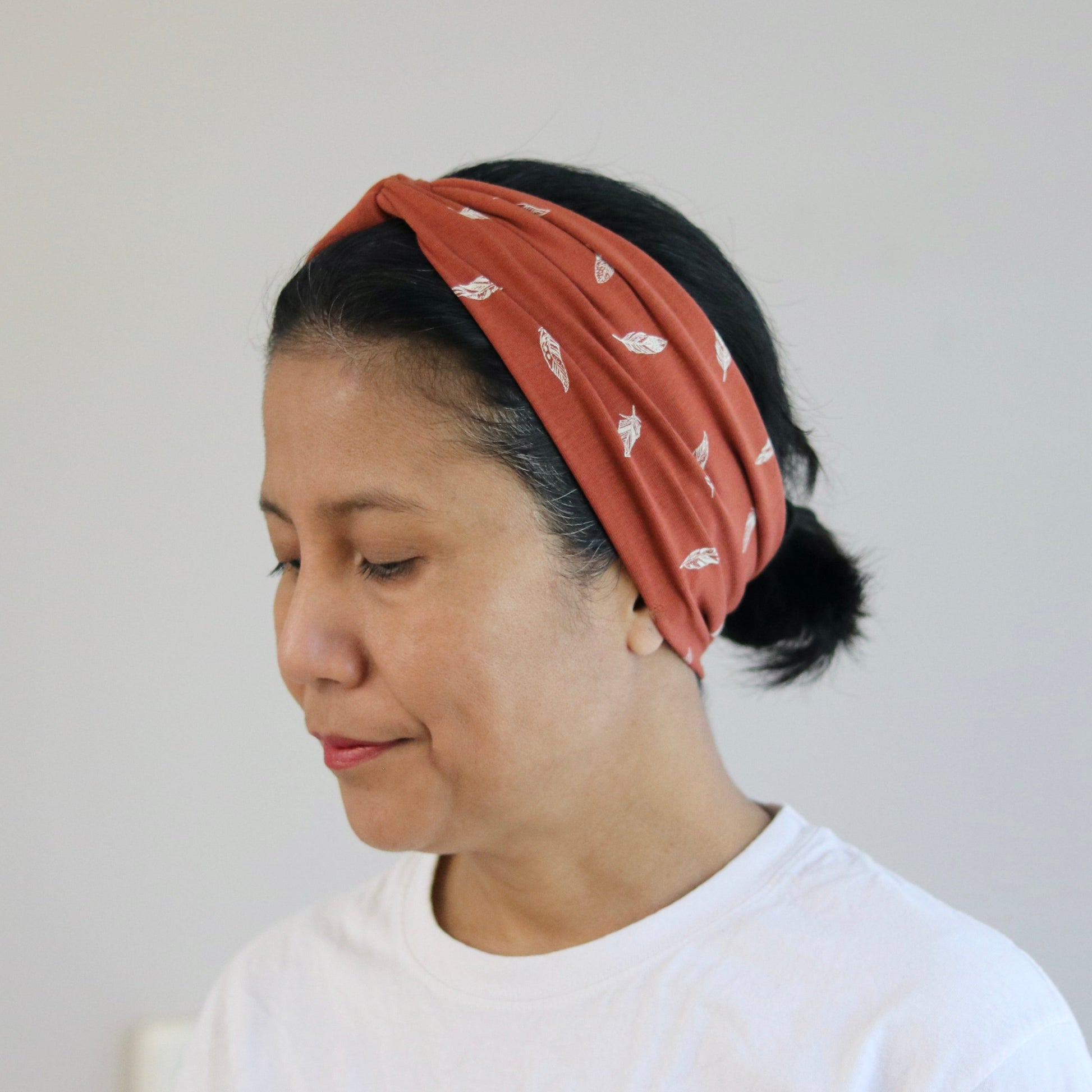 Woman wearing a rust patterned headband against a plain background