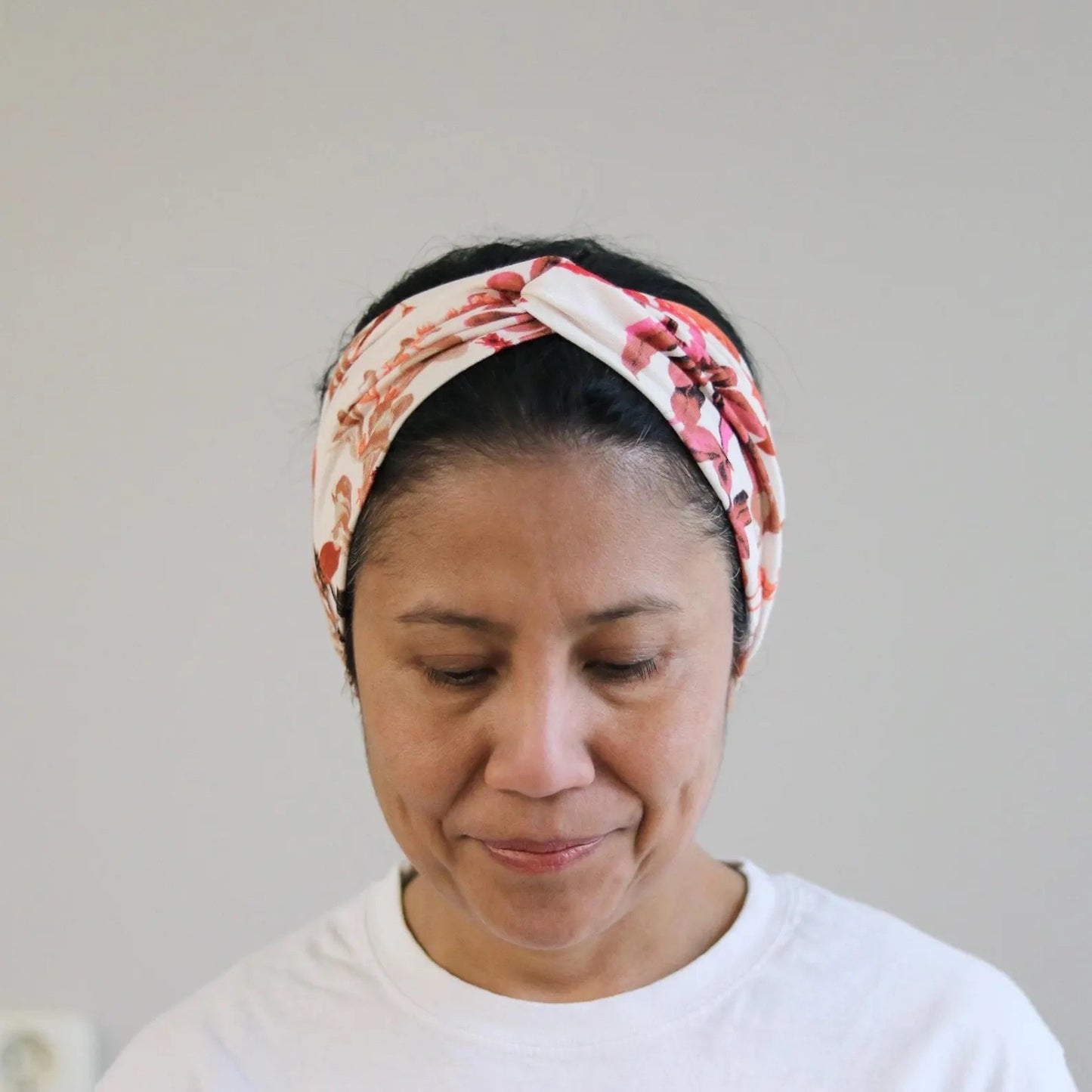 Woman wearing a floral headband against a plain background