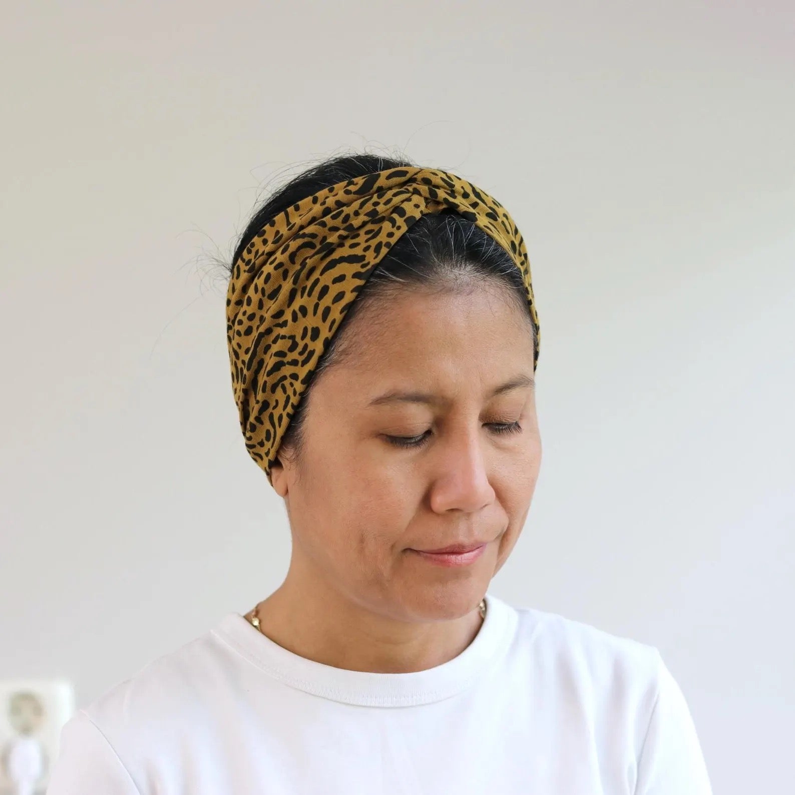 Woman wearing a leopard print headband against a plain background