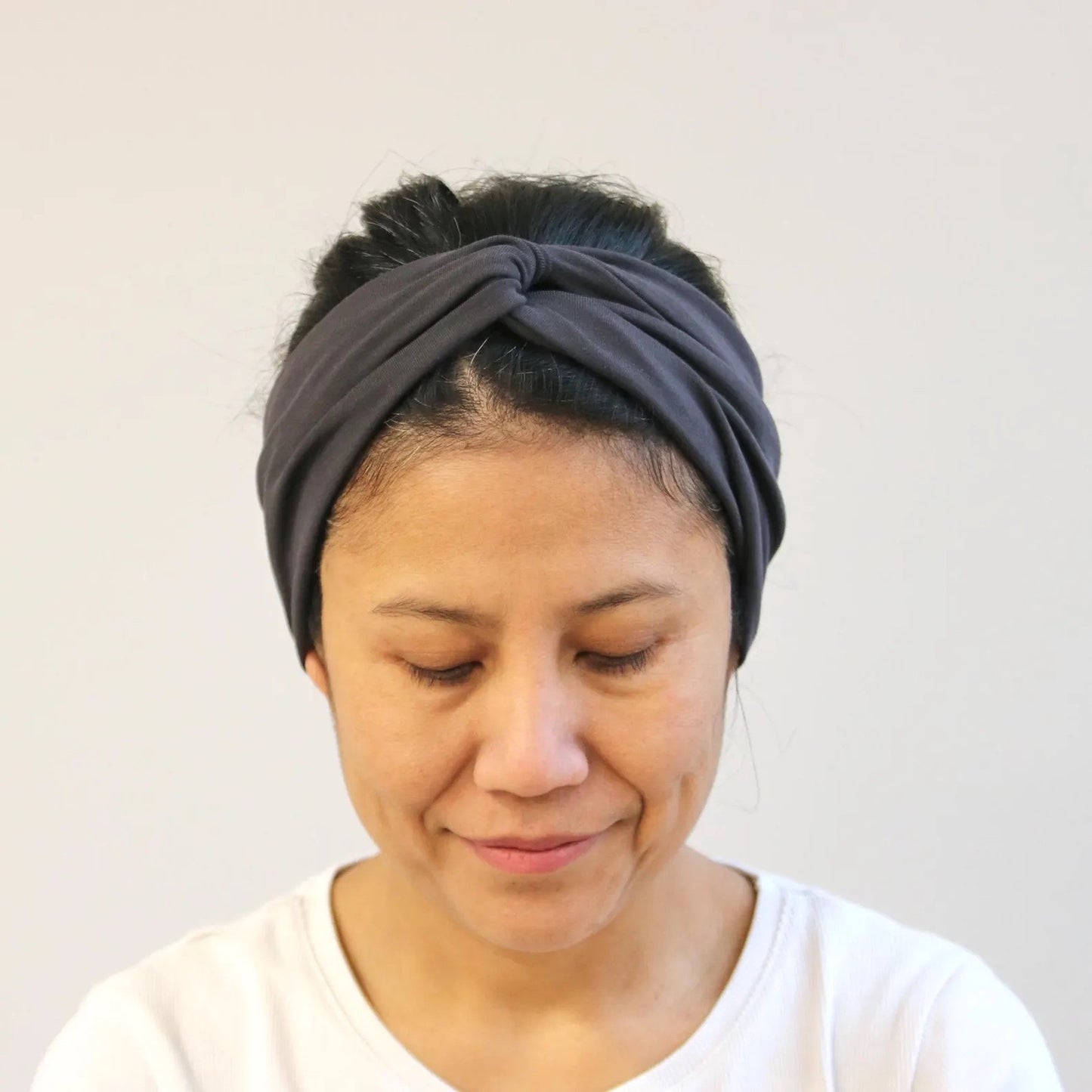 Woman wearing a gray headband against a plain background