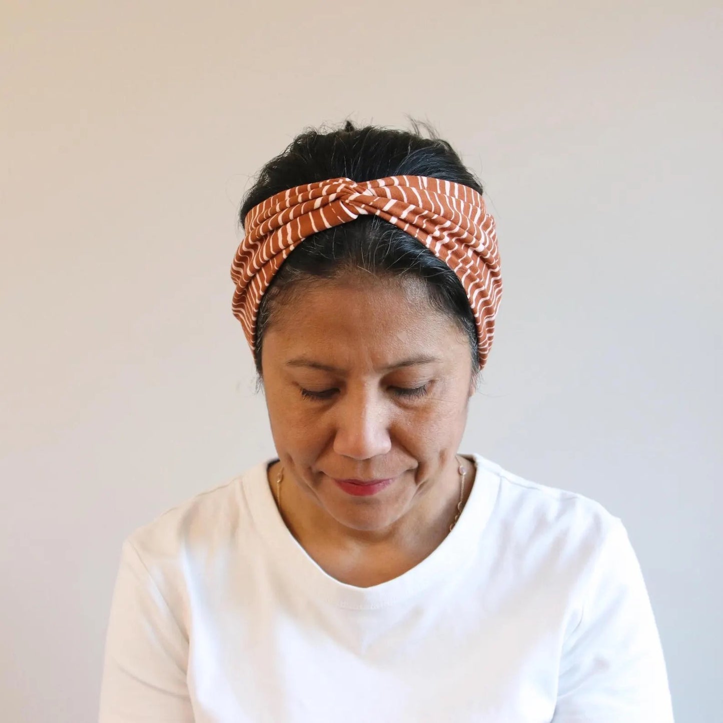 Woman wearing a brown patterned headband against a plain background
