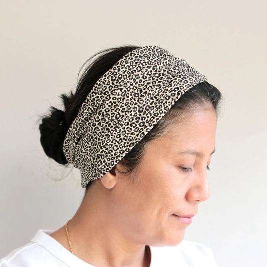 Person wearing a leopard print headband against a plain background