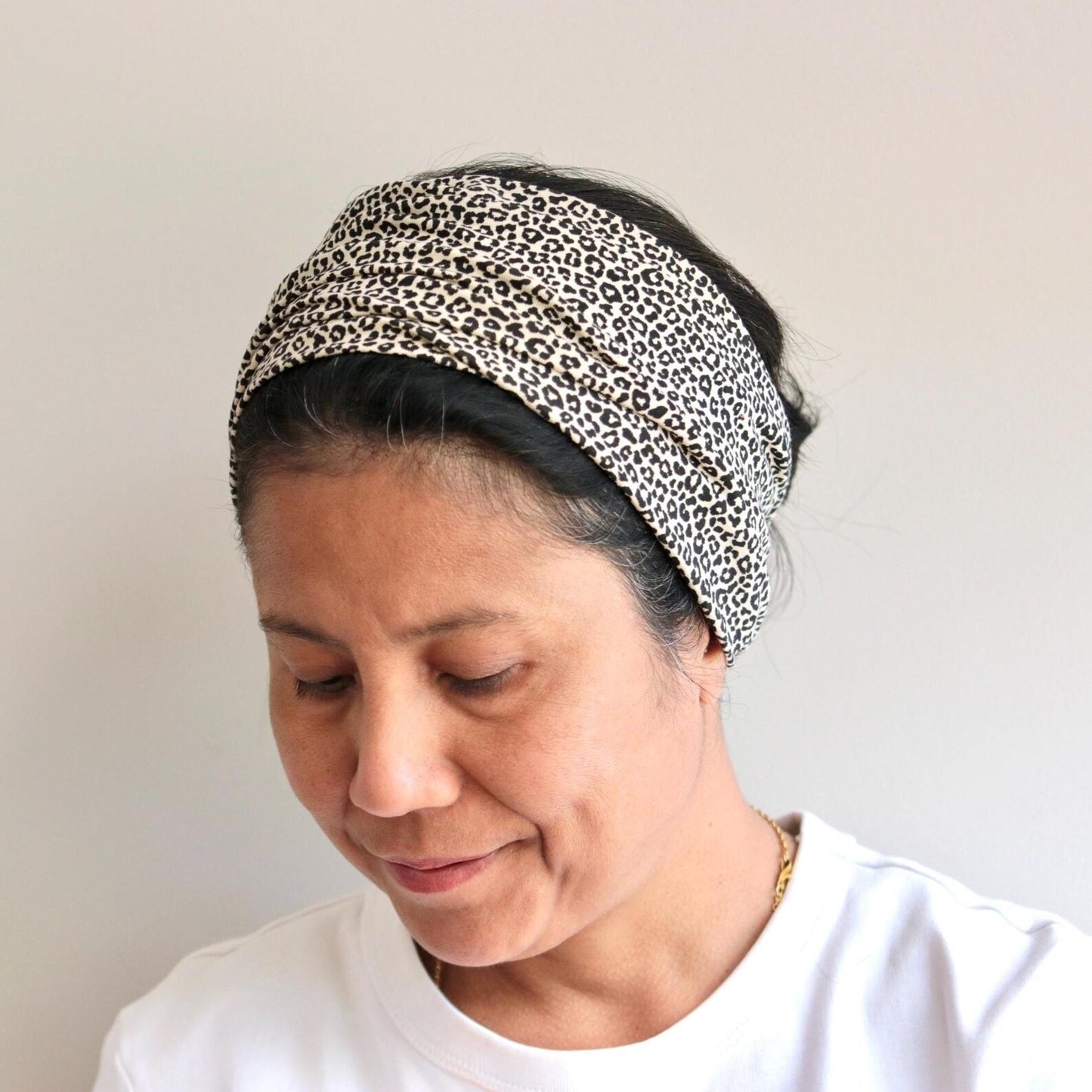 Person wearing a leopard print headband against a plain background