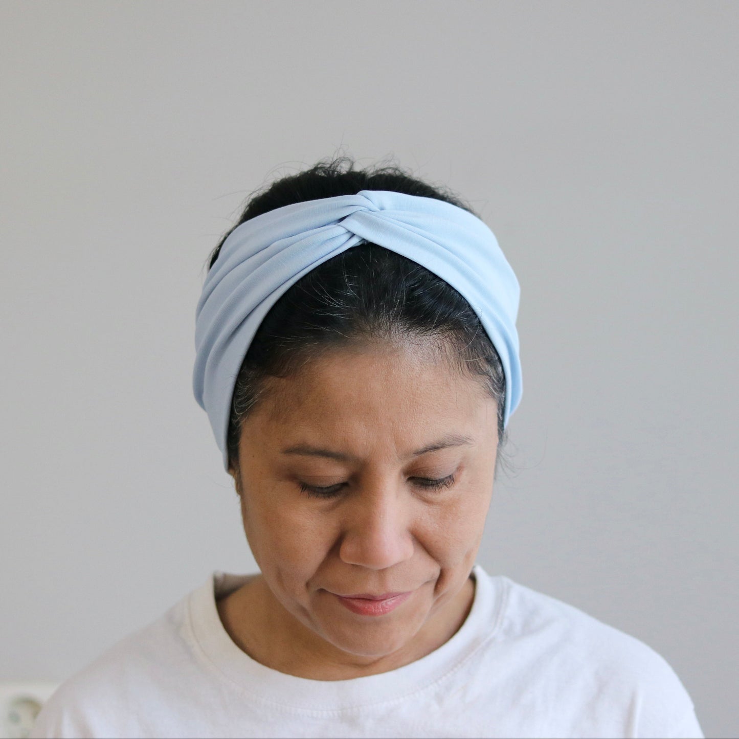 Woman wearing a light blue headband against a plain background