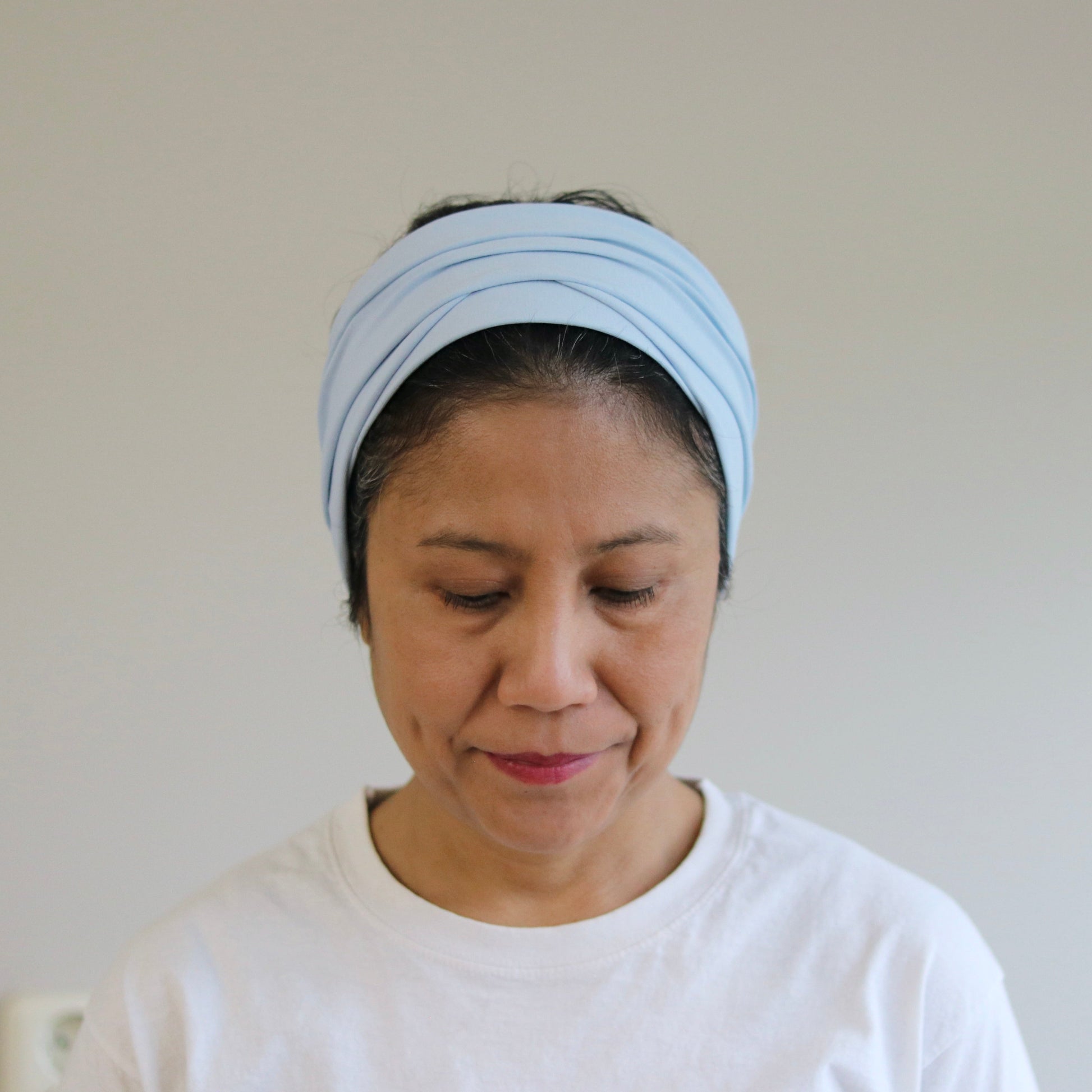 Woman wearing a light blue headband against a plain background