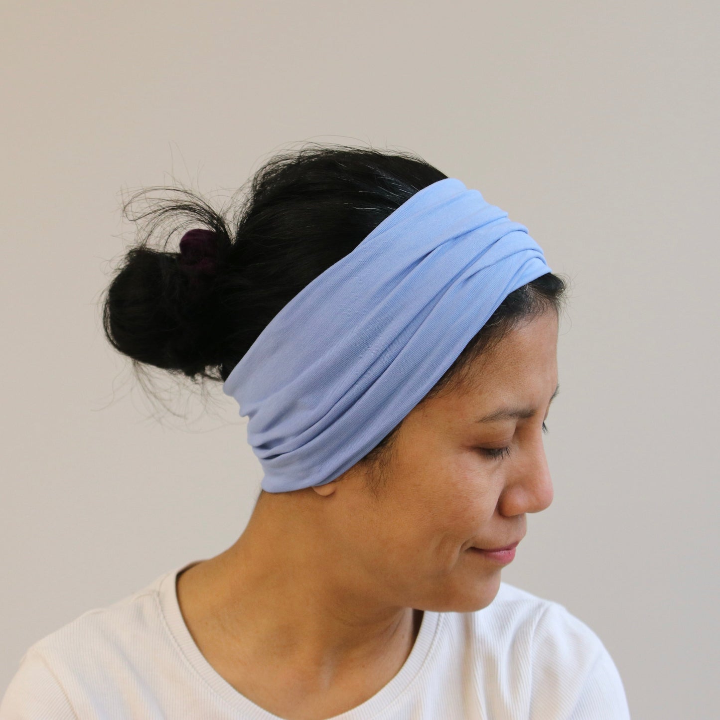 Woman wearing a light blue headband against a plain background