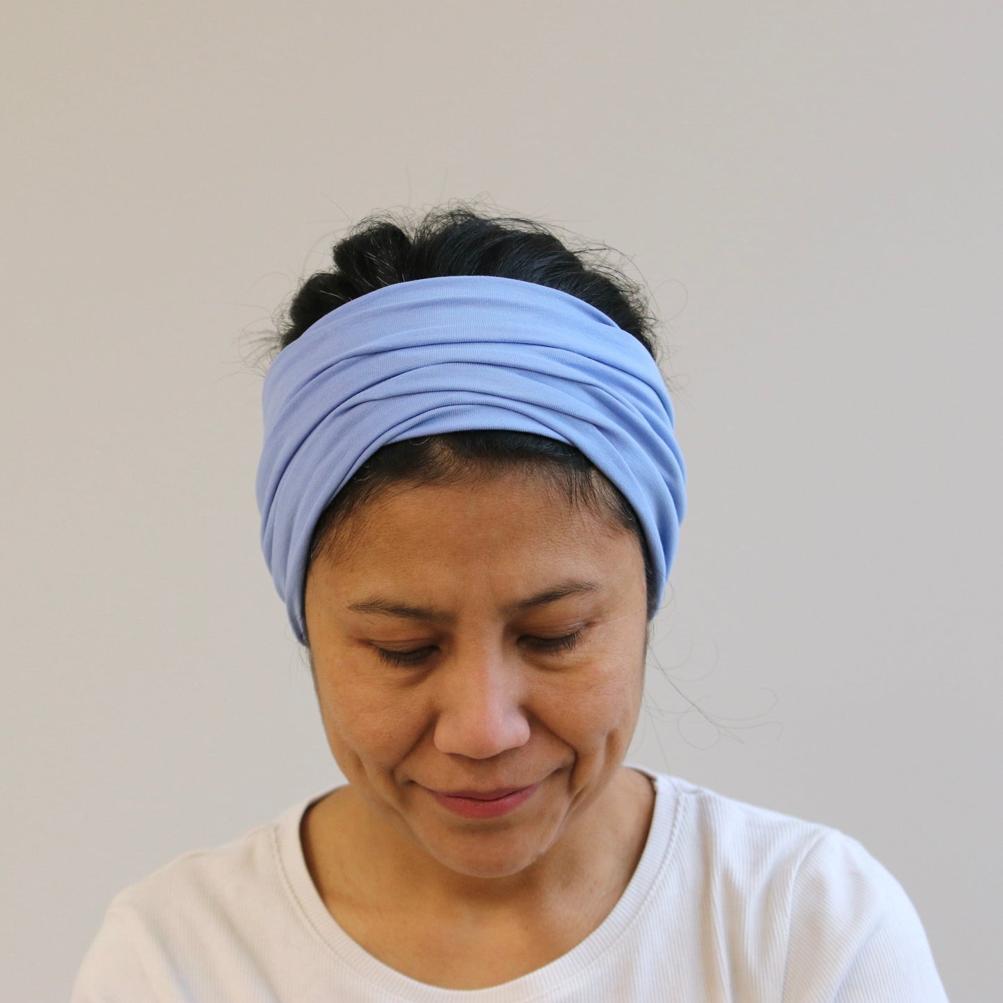 Woman wearing a light blue headband against a plain background