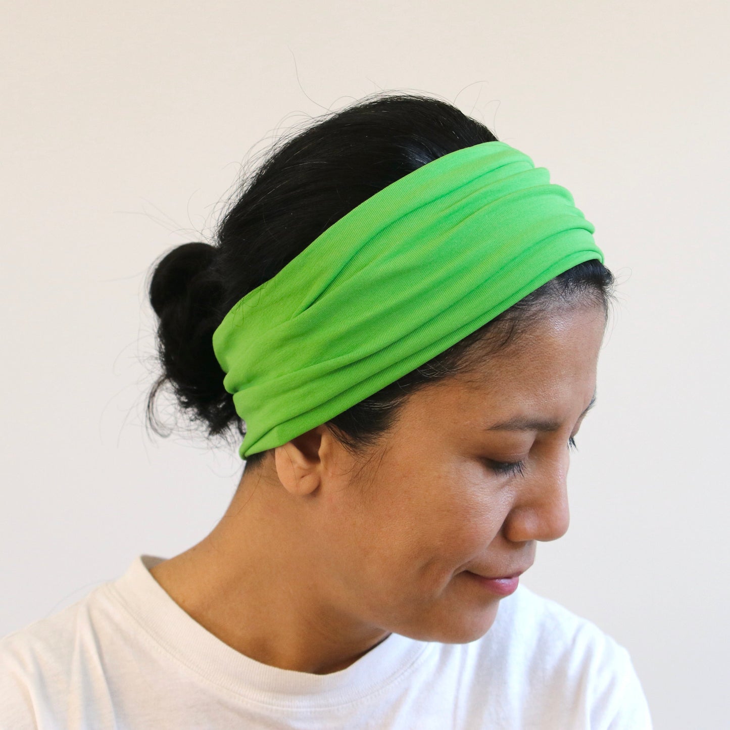 Person wearing a bright green headband against a plain background