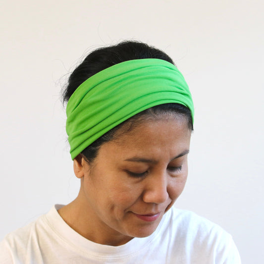 Person wearing a green headband against a plain background