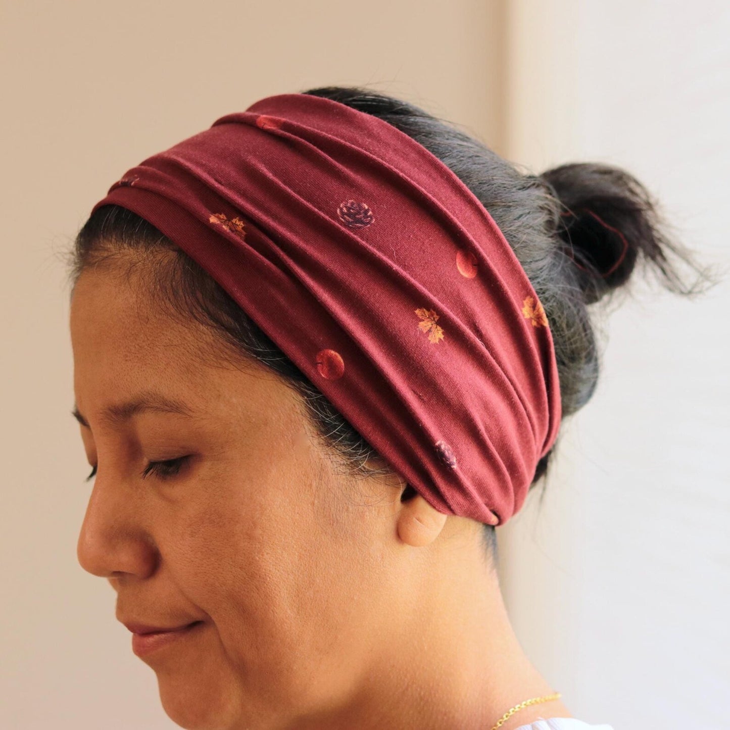 Woman wearing a maroon headband with floral patterns on a neutral background