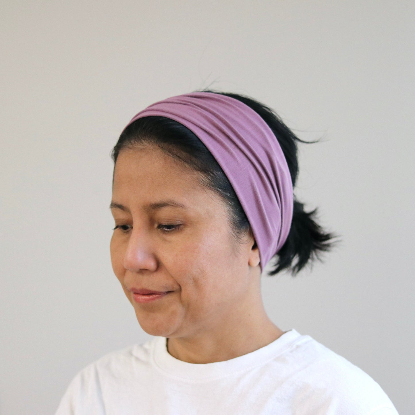 Woman wearing a purple headband against a plain background
