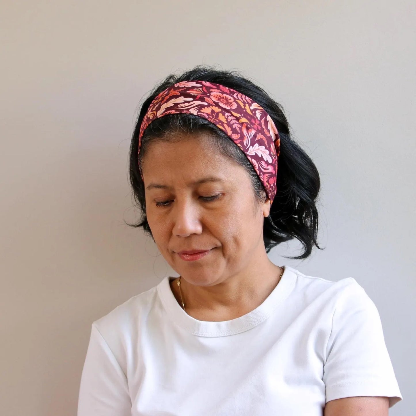 Woman wearing a patterned headband against a plain background