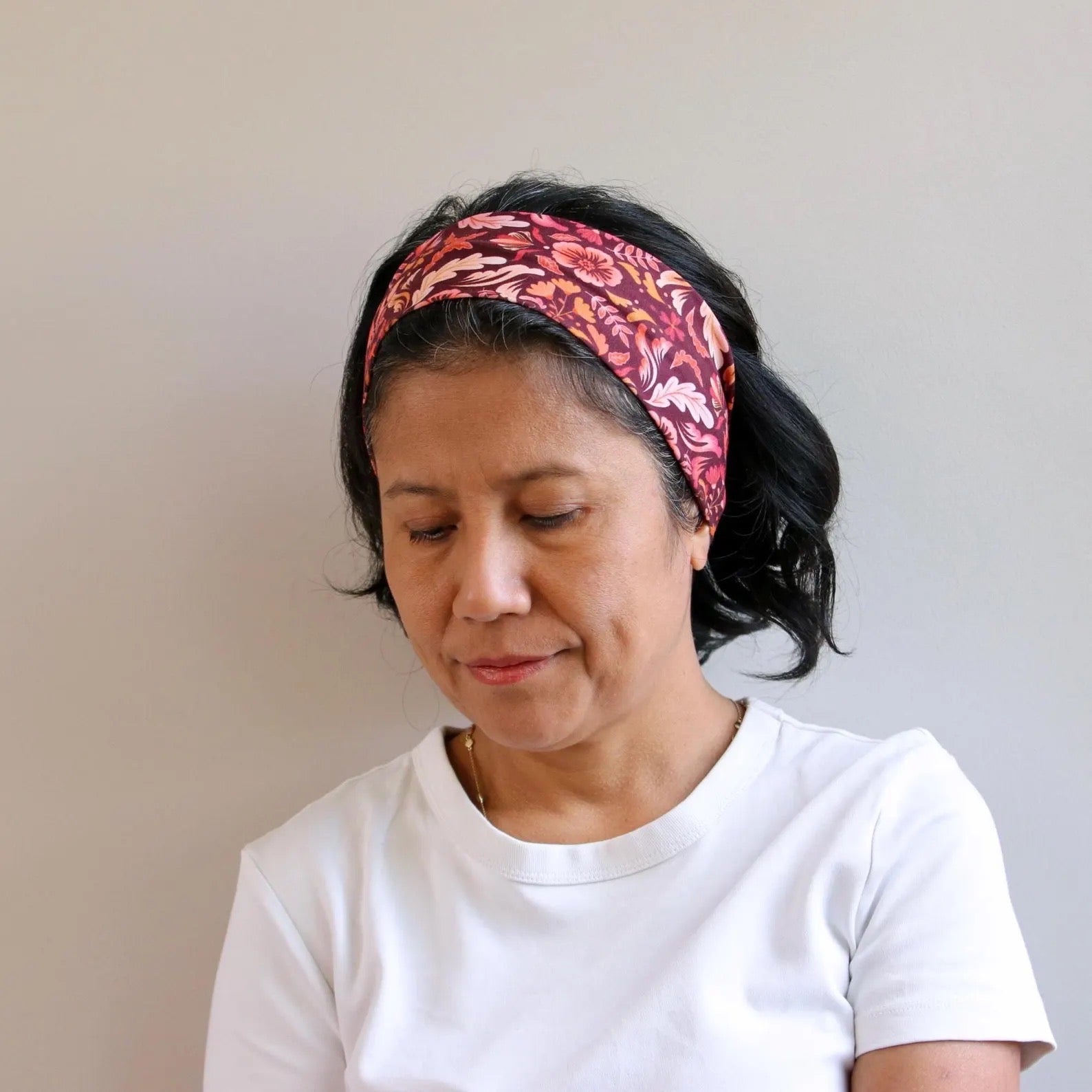 Woman wearing a patterned headband against a plain background