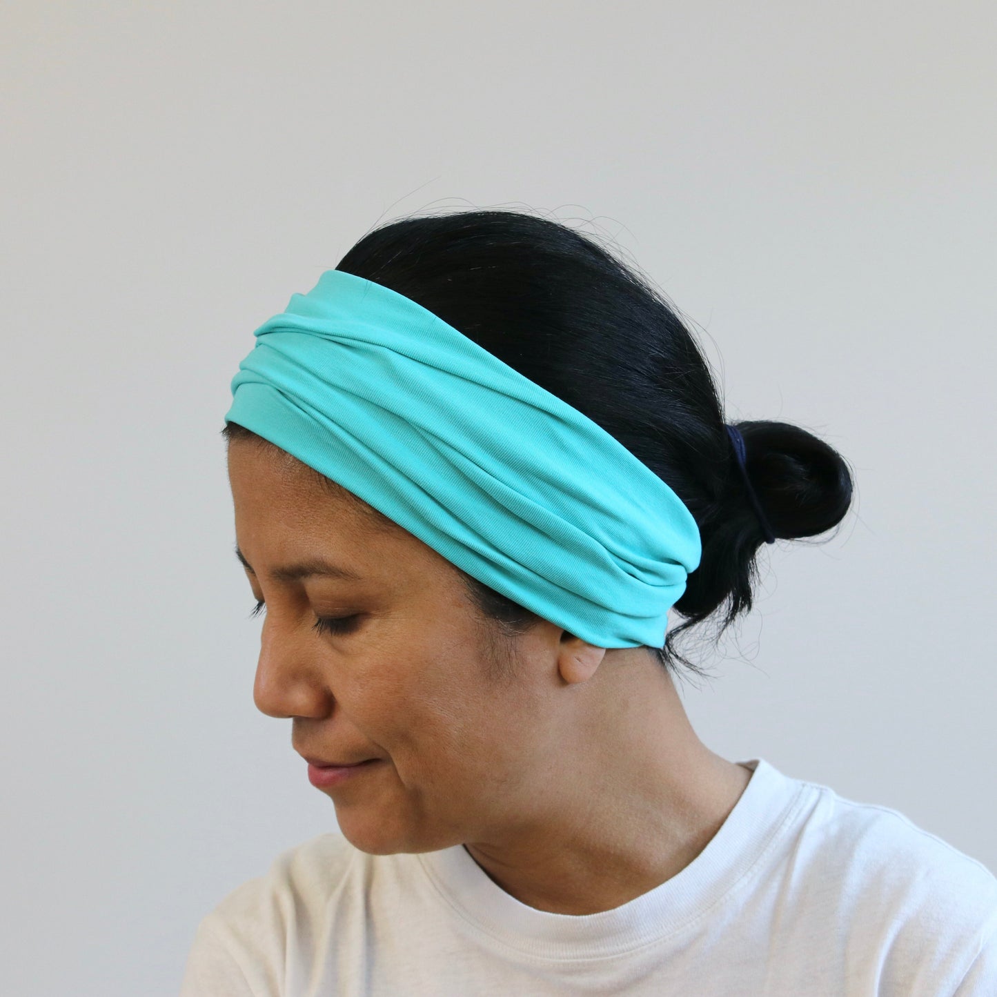 Woman wearing a turquoise headband against a plain background